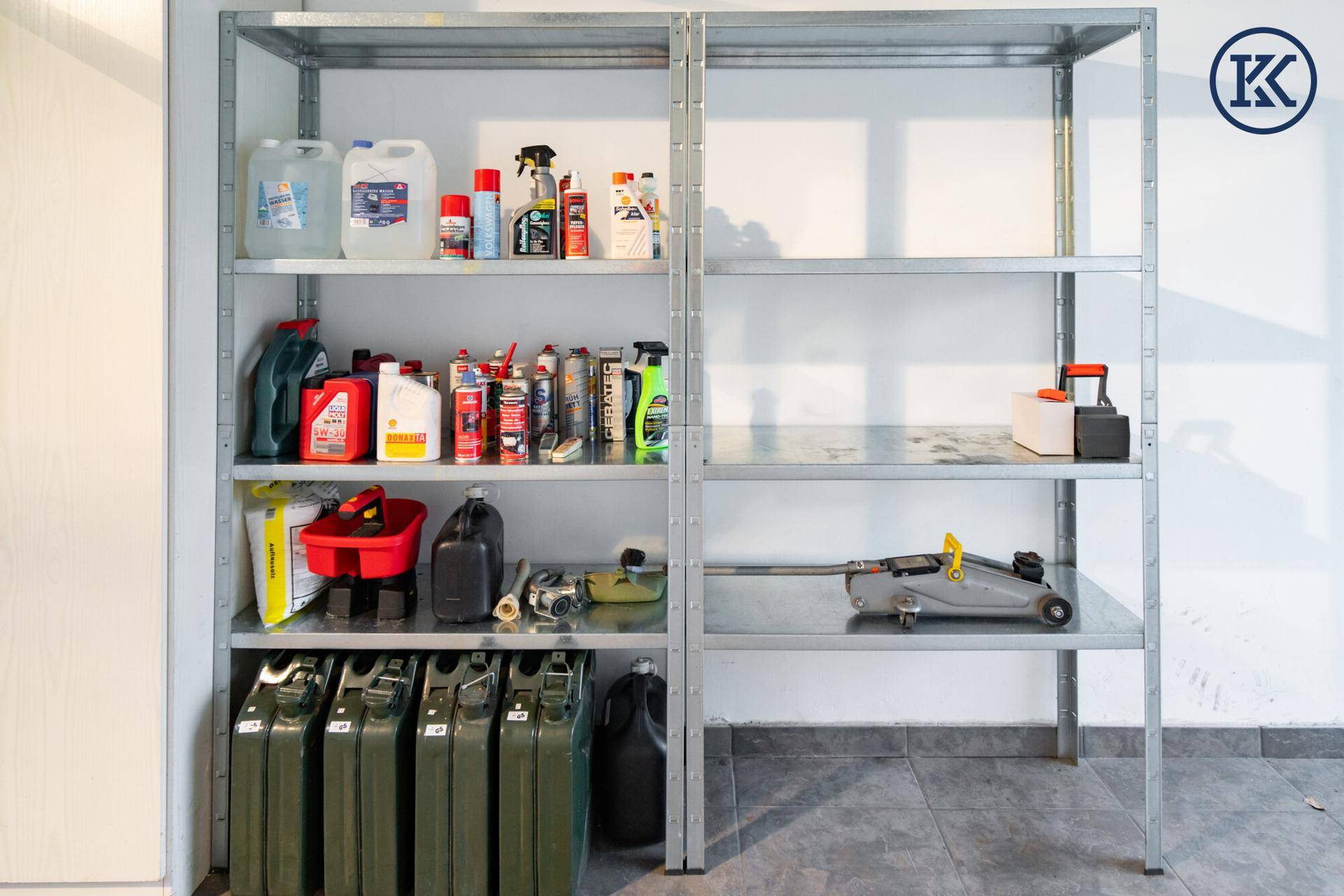 Nahaufnahme von Metallregalen in der Garage, gefüllt mit verschiedenen Flüssigkeiten, Werkzeugen und Kanistern.