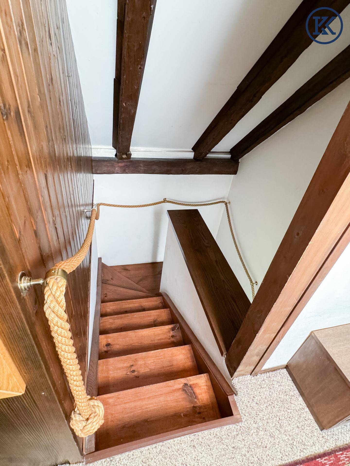 Rustikale Holztreppe mit Seilgeländer, die in den unteren Bereich führt.