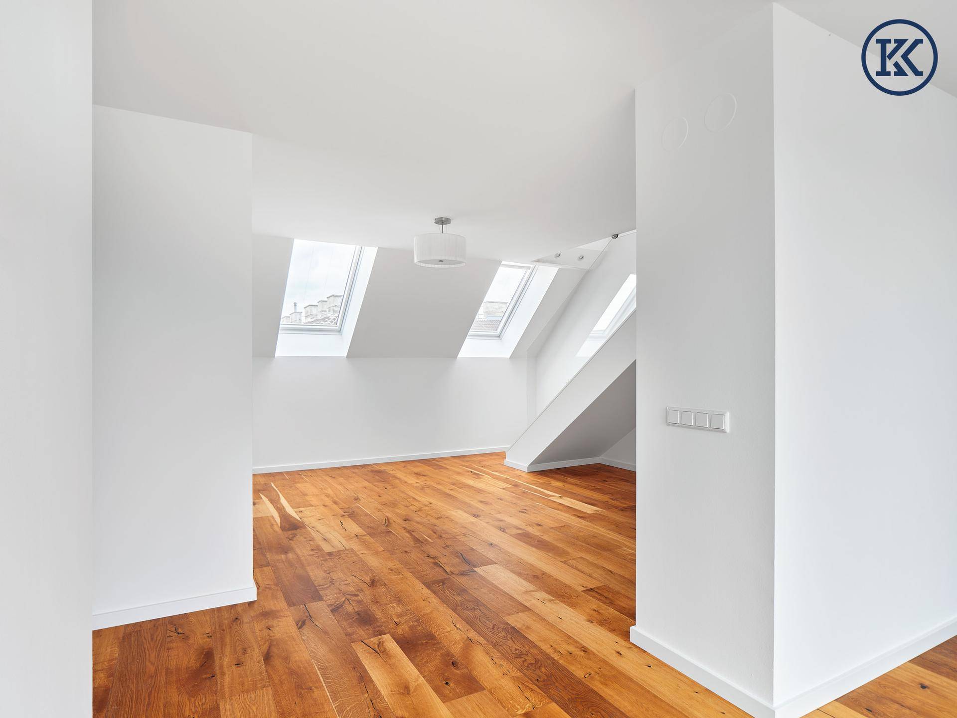 Geräumiger, heller Raum mit Holzboden und mehreren Dachfenstern.