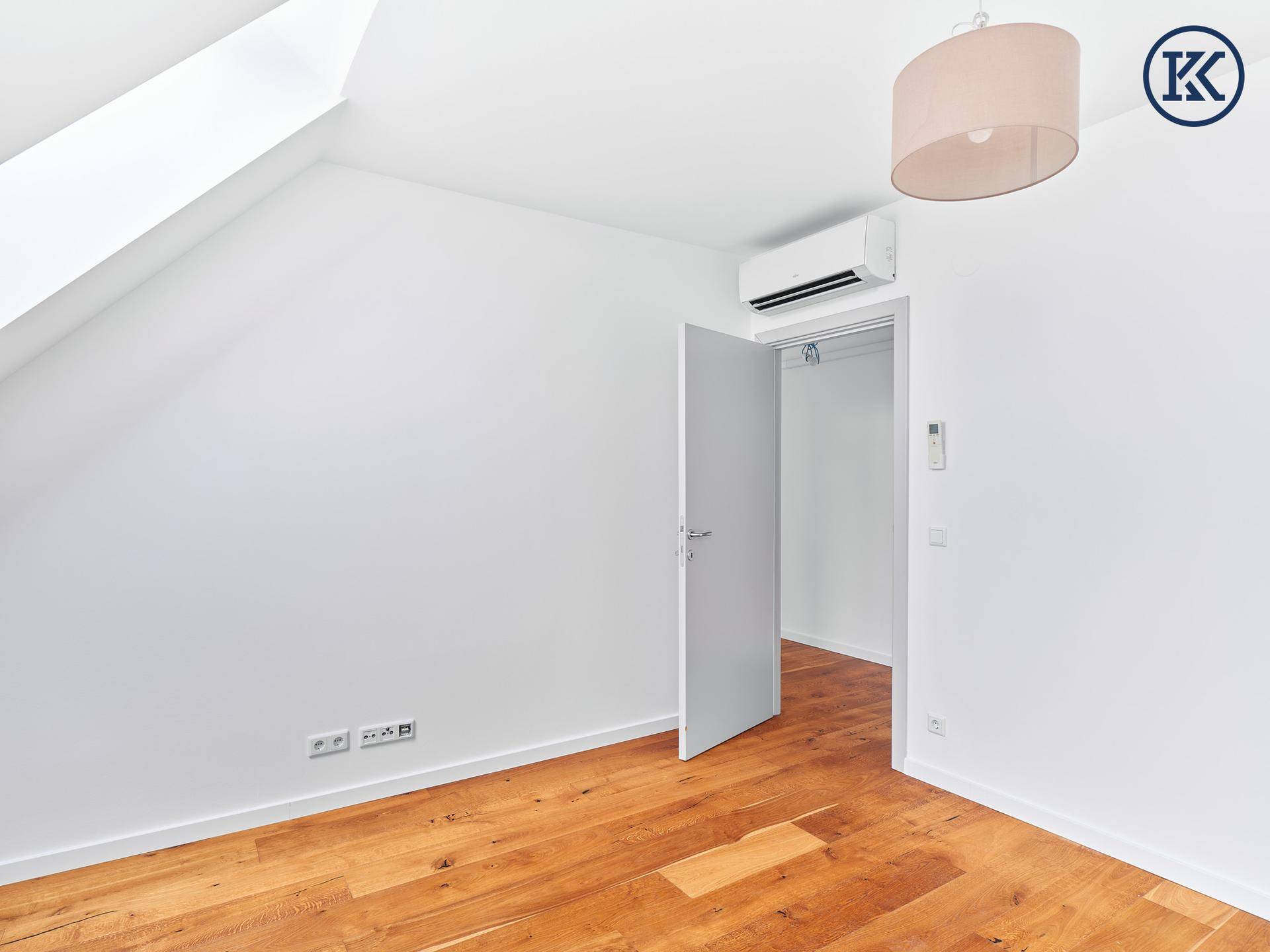 Schlafzimmer mit Holzboden, Klimaanlage und Zugang zu einem Schrankbereich.