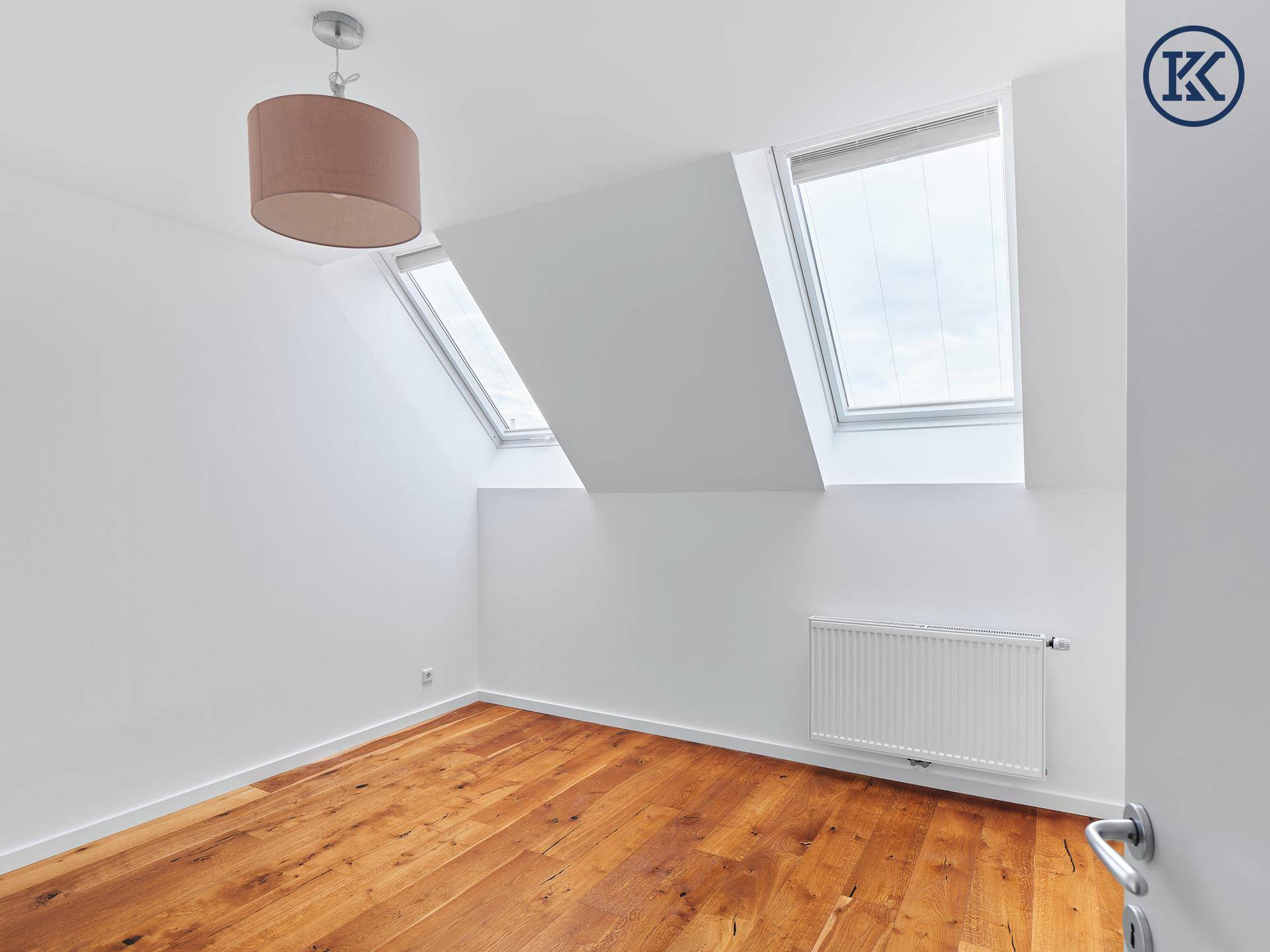 Helles Schlafzimmer mit Holzboden, Dachfenstern und Heizkörper.