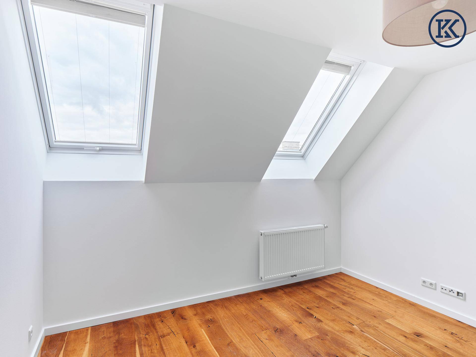 Schlafzimmer mit Holzboden, zwei Dachfenstern und Heizkörper.