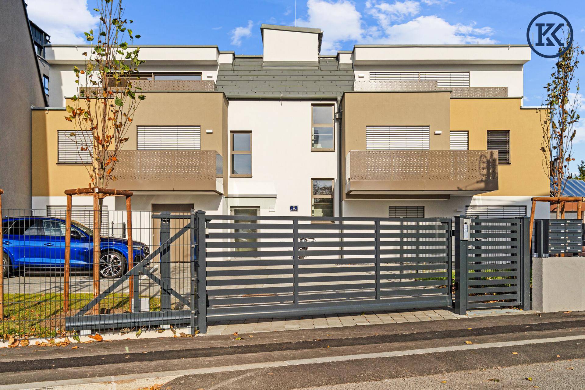 Moderne Wohnanlage mit ansprechender Fassade, privatem Eingangstor und Stellplatz für Fahrzeuge.