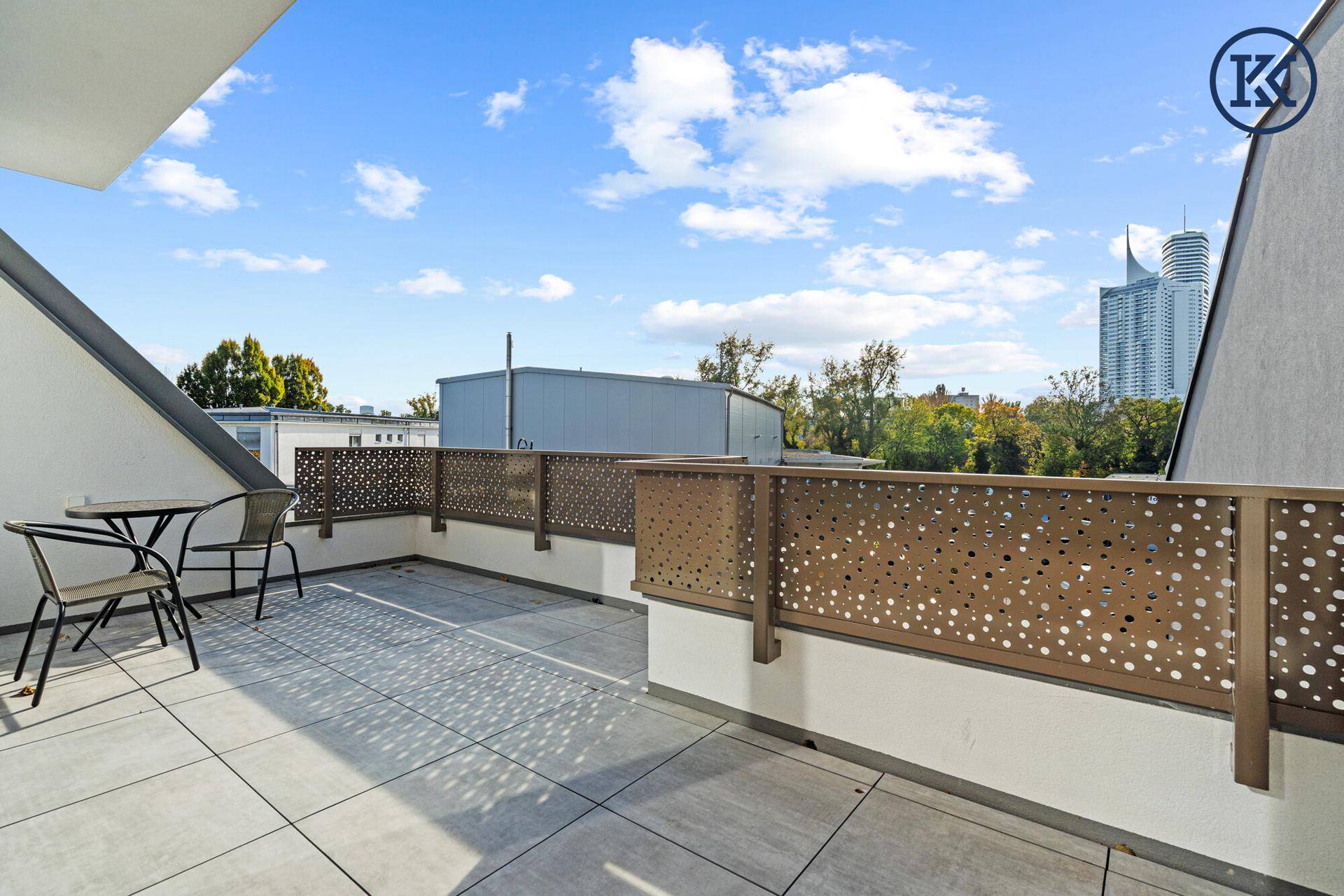 Geräumige Dachterrasse mit Fliesenboden, Sitzgelegenheiten und Blick auf die Stadt.