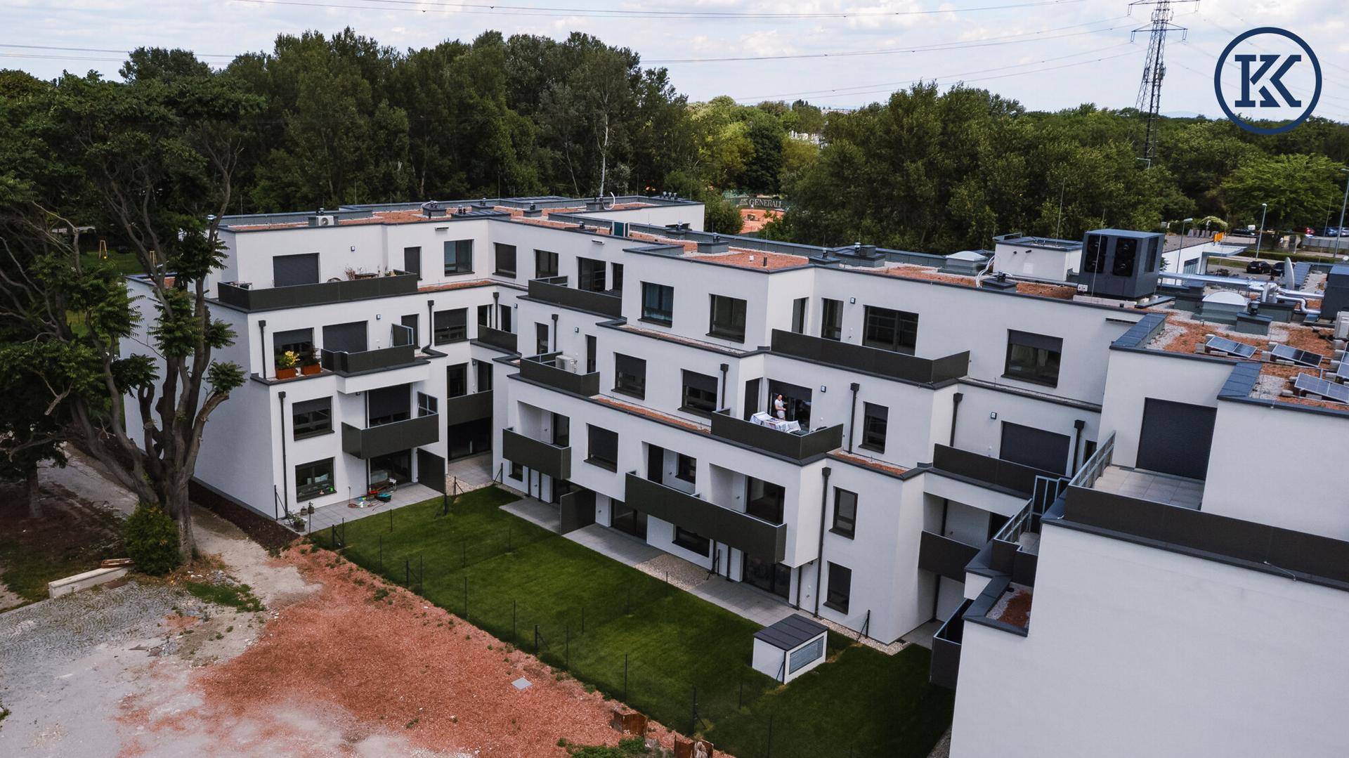 Luftaufnahme des Innenhofs des Wohnkomplexes mit gepflegtem Rasen und Bäumen.