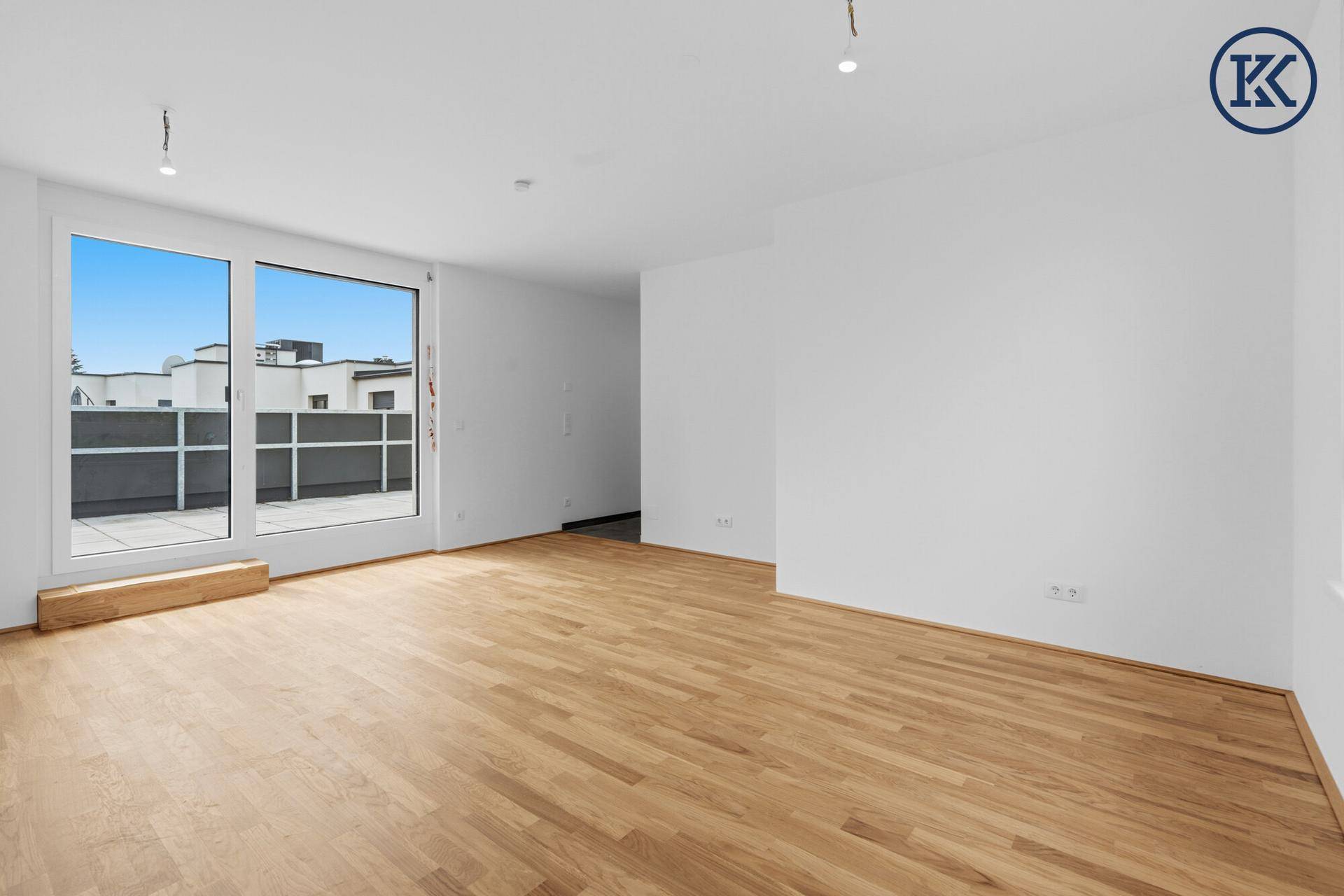 Helles Zimmer mit Parkettboden und Zugang zu einer großen Terrasse.