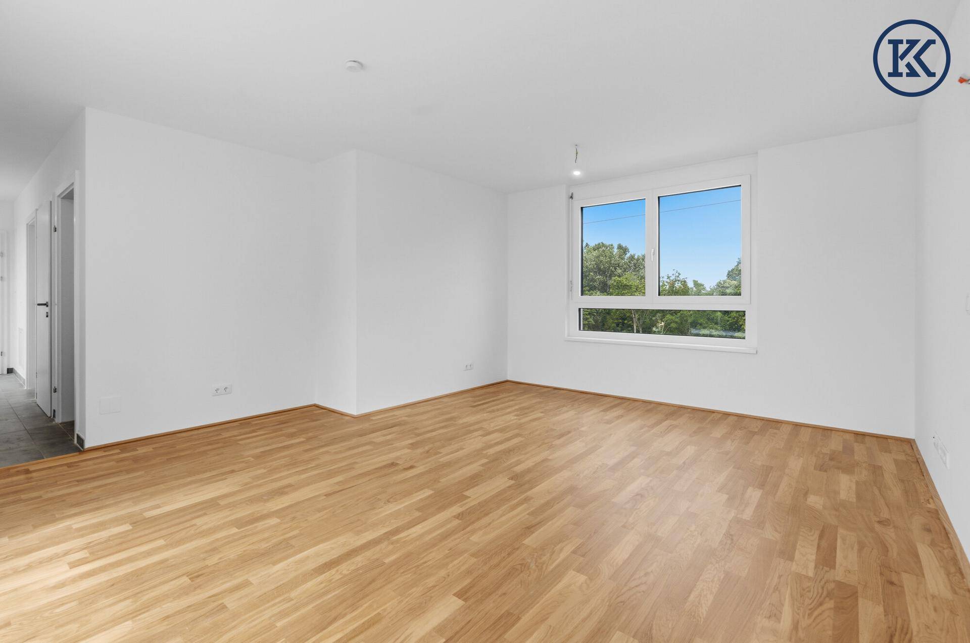 Geräumiges, helles Zimmer mit Parkettboden und großem Fenster mit Ausblick.
