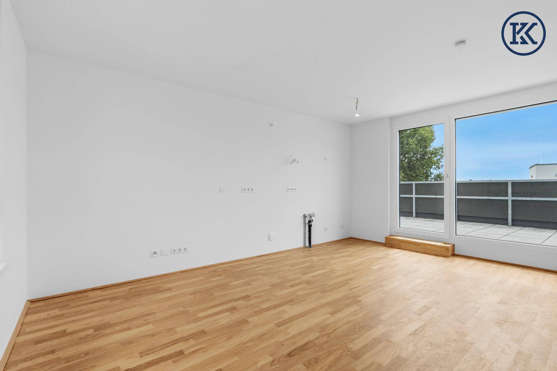 Leeres, helles Zimmer mit Parkettboden und direktem Zugang zur Außenterrasse.