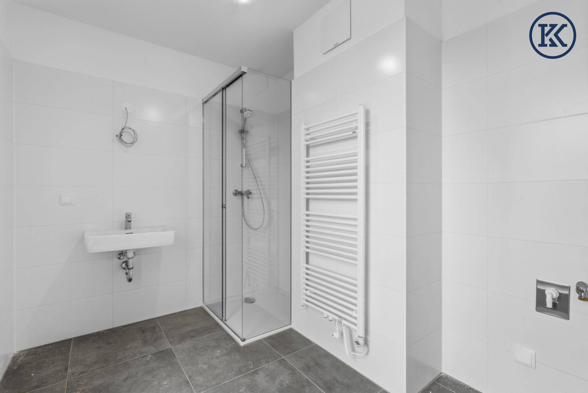 Modernes Badezimmer mit Dusche, Waschbecken und Handtuchheizkörper, hell gefliest.