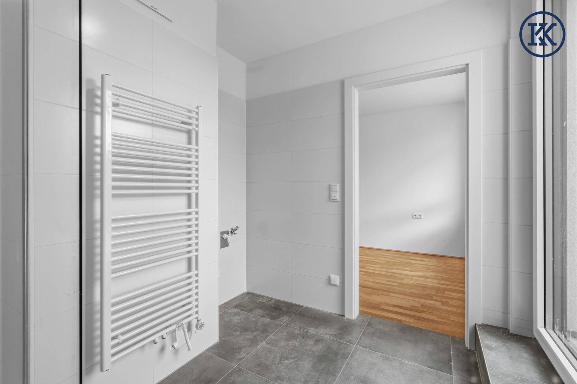 Modernes Badezimmer mit Handtuchheizkörper und Blick in einen angrenzenden Raum.