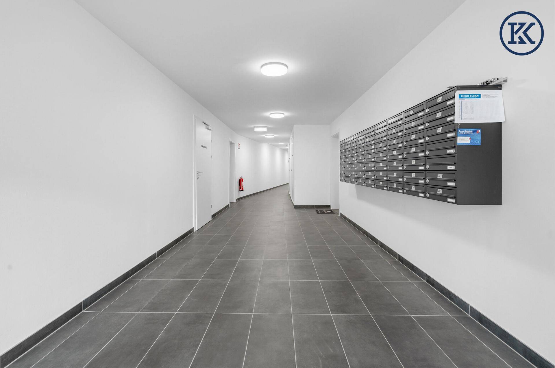 Langer Flur mit Briefkästen und Fliesenboden in der modernen Wohnanlage.