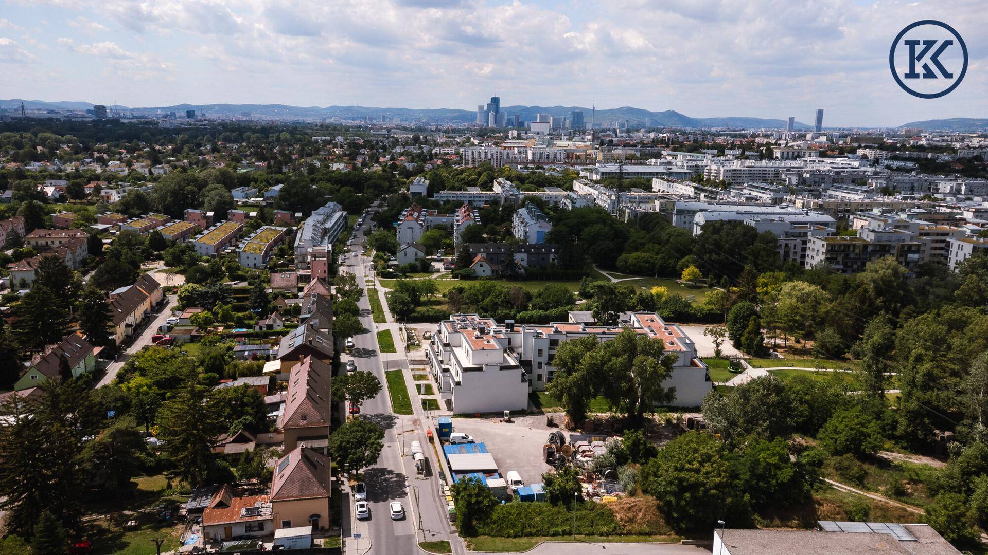 Weitläufige Luftaufnahme der Wohngegend mit viel Grün und Stadtblick.