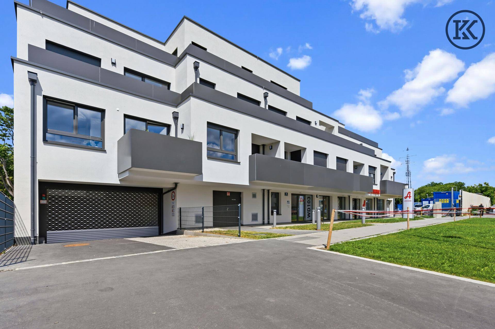 Eingangsbereich der Wohnanlage mit Garagenzufahrt und modernen Fassadenelementen.