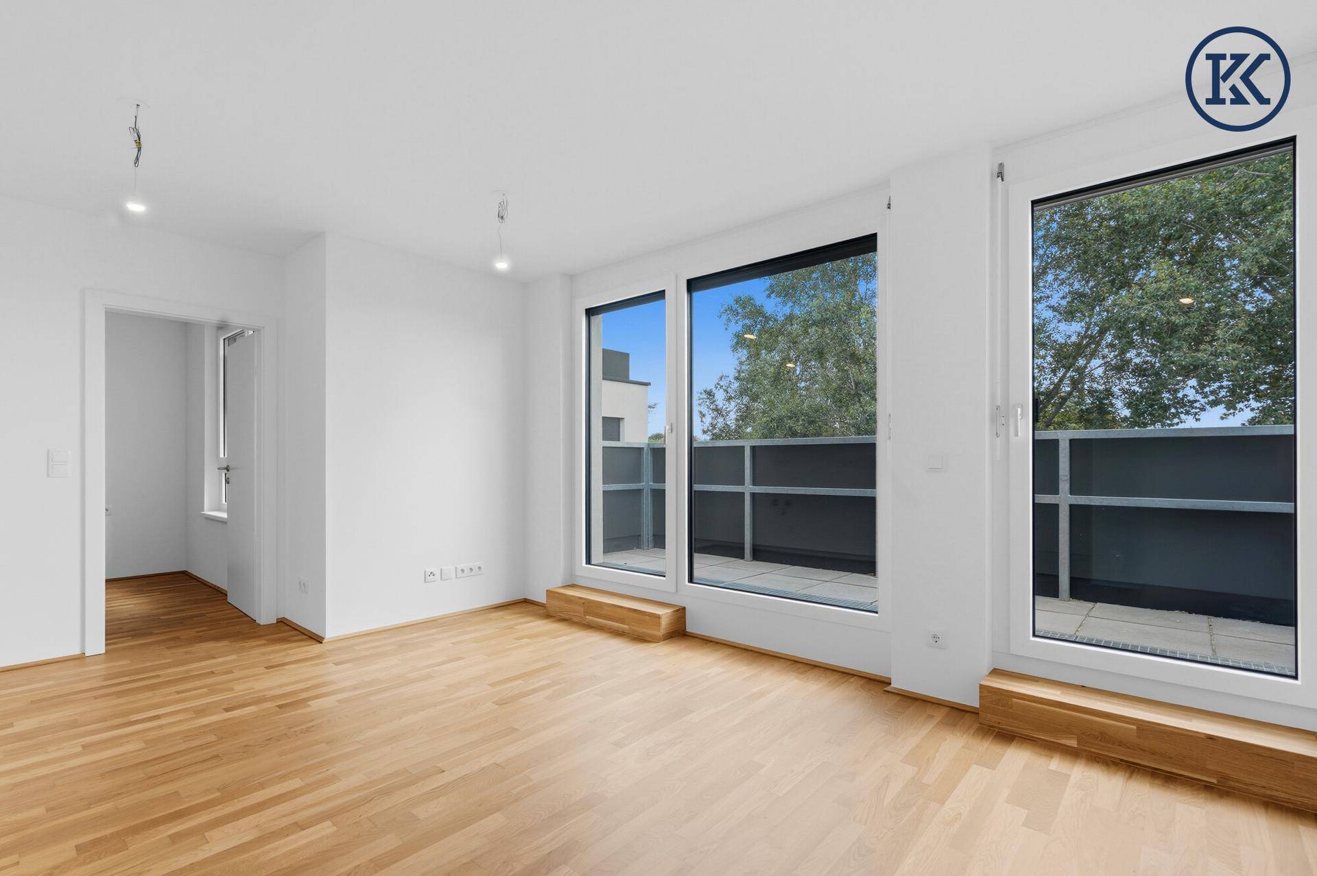 Helles Wohnzimmer mit Parkettboden und großen Fenstern zum Balkon.