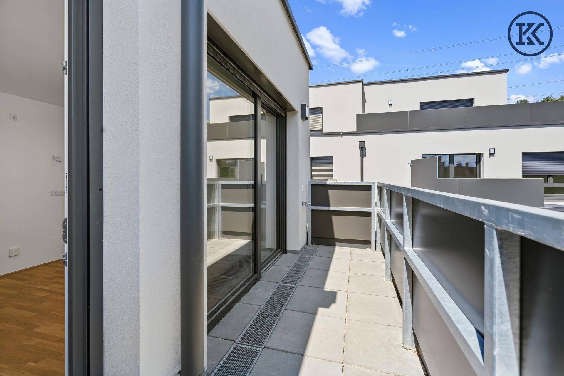 Heller Balkon mit Fliesenboden und Blick auf die Umgebung.