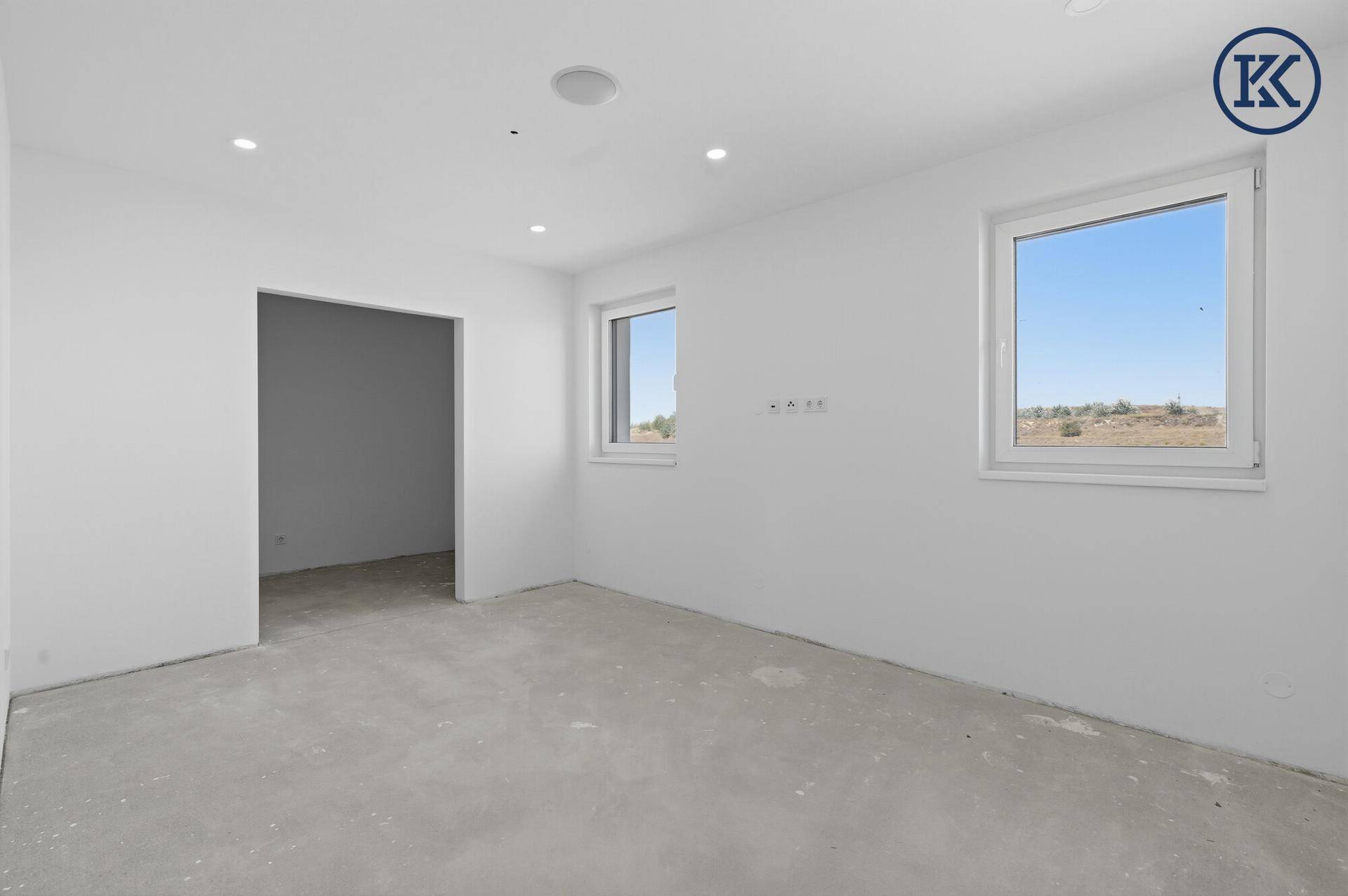 Helles Zimmer im Neubau mit zwei Fenstern und Blick auf die Umgebung.