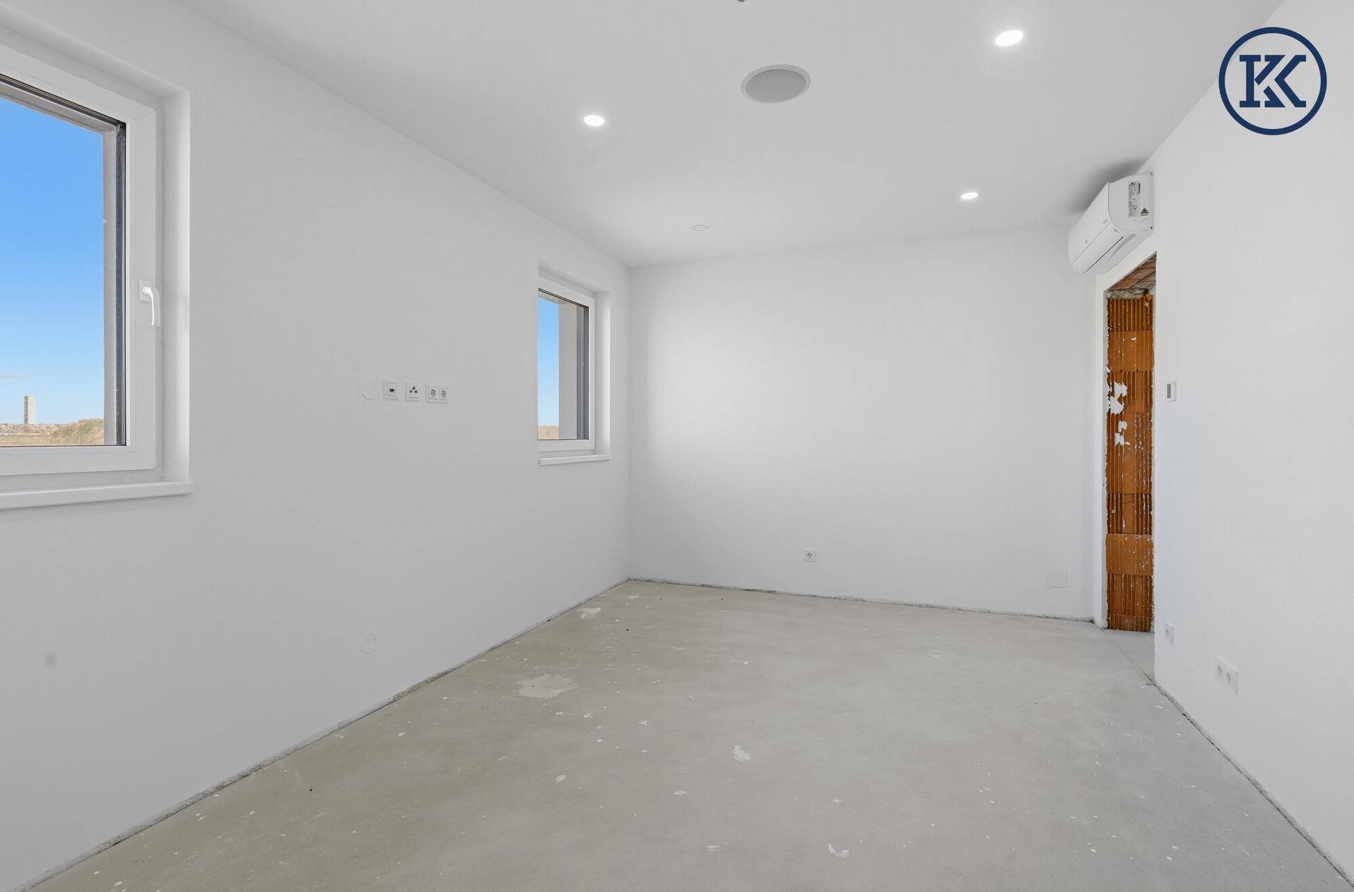 Helles Zimmer im Neubau mit Klimaanlage, zwei Fenstern und Blick ins Grüne.