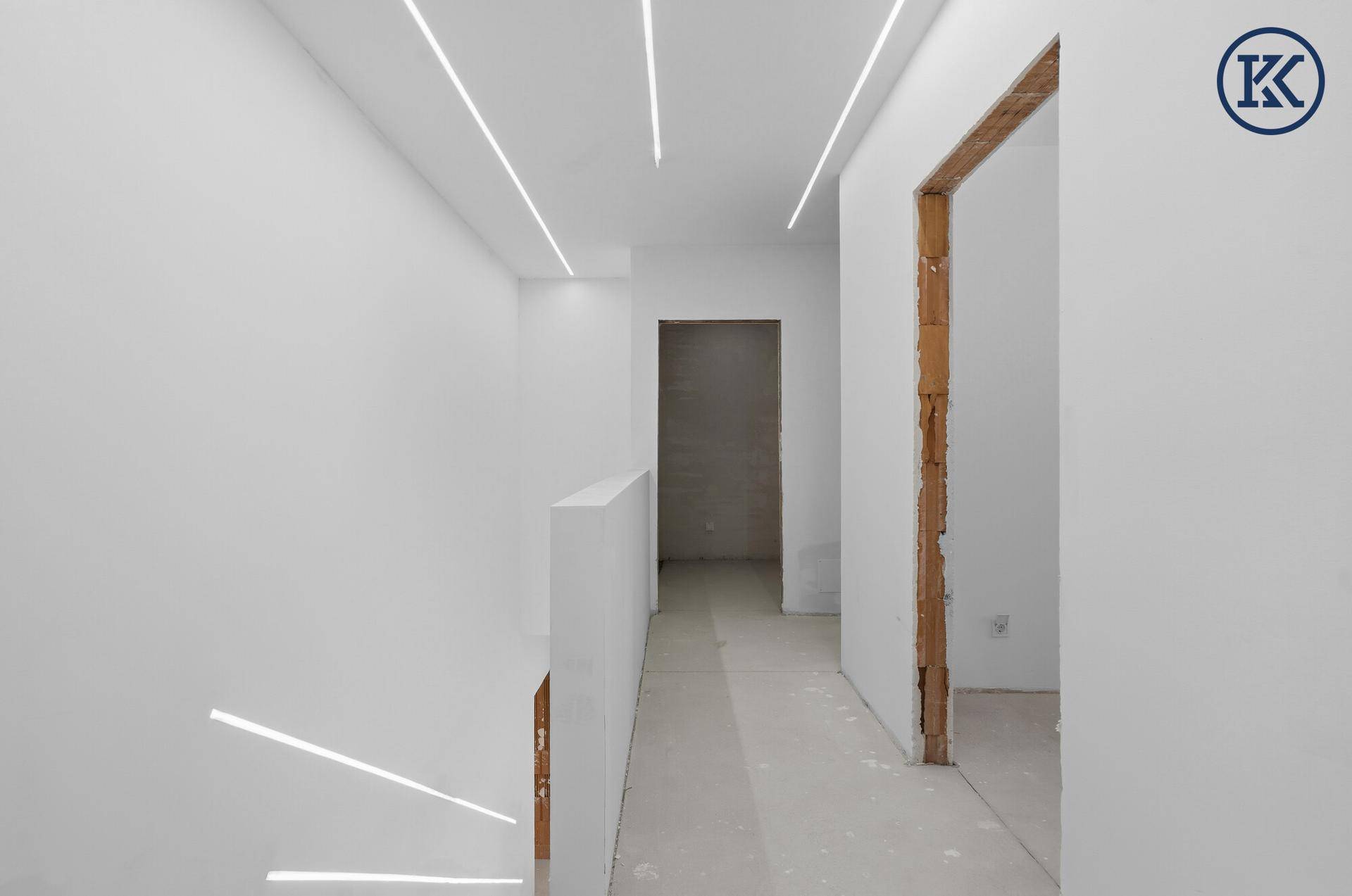 Heller Flur im Neubau mit moderner Deckenbeleuchtung und Blick auf den Treppenaufgang.