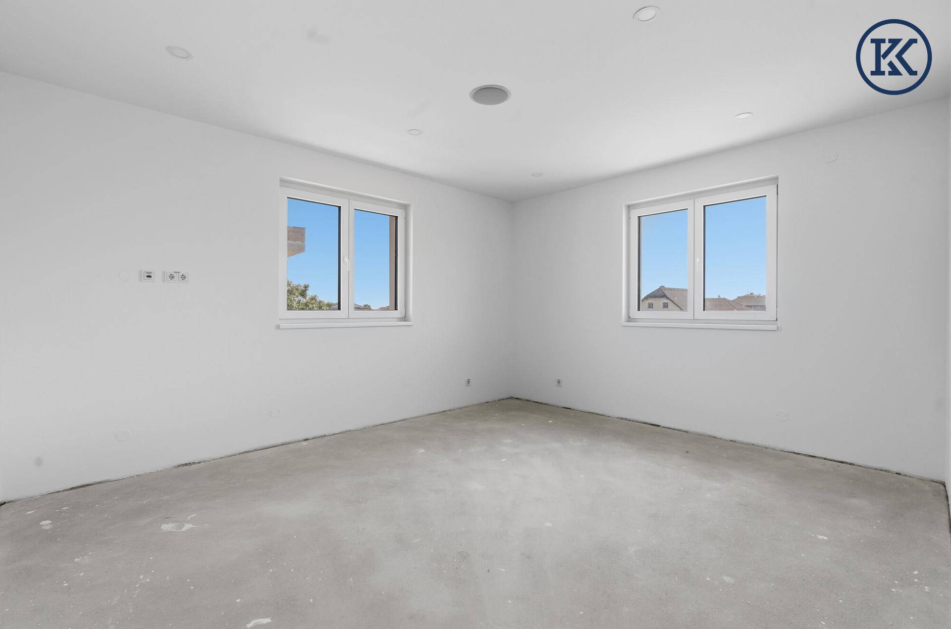 Helles Zimmer im Neubau mit zwei Fenstern und Blick auf die umliegenden Häuser.