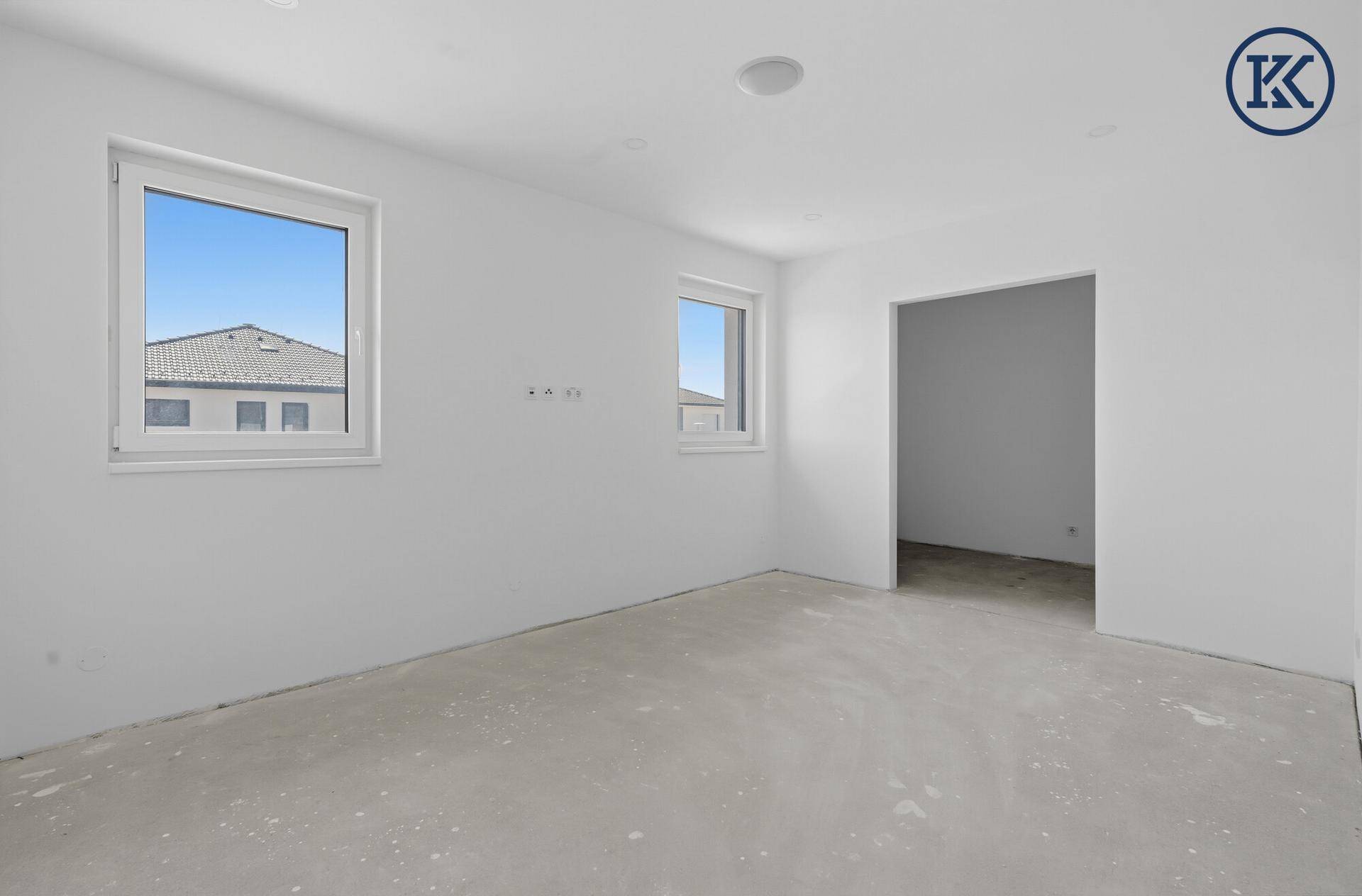 Leerer Raum im Neubau mit zwei Fenstern und weiß gestrichenen Wänden, bereit für die individuelle Gestaltung.