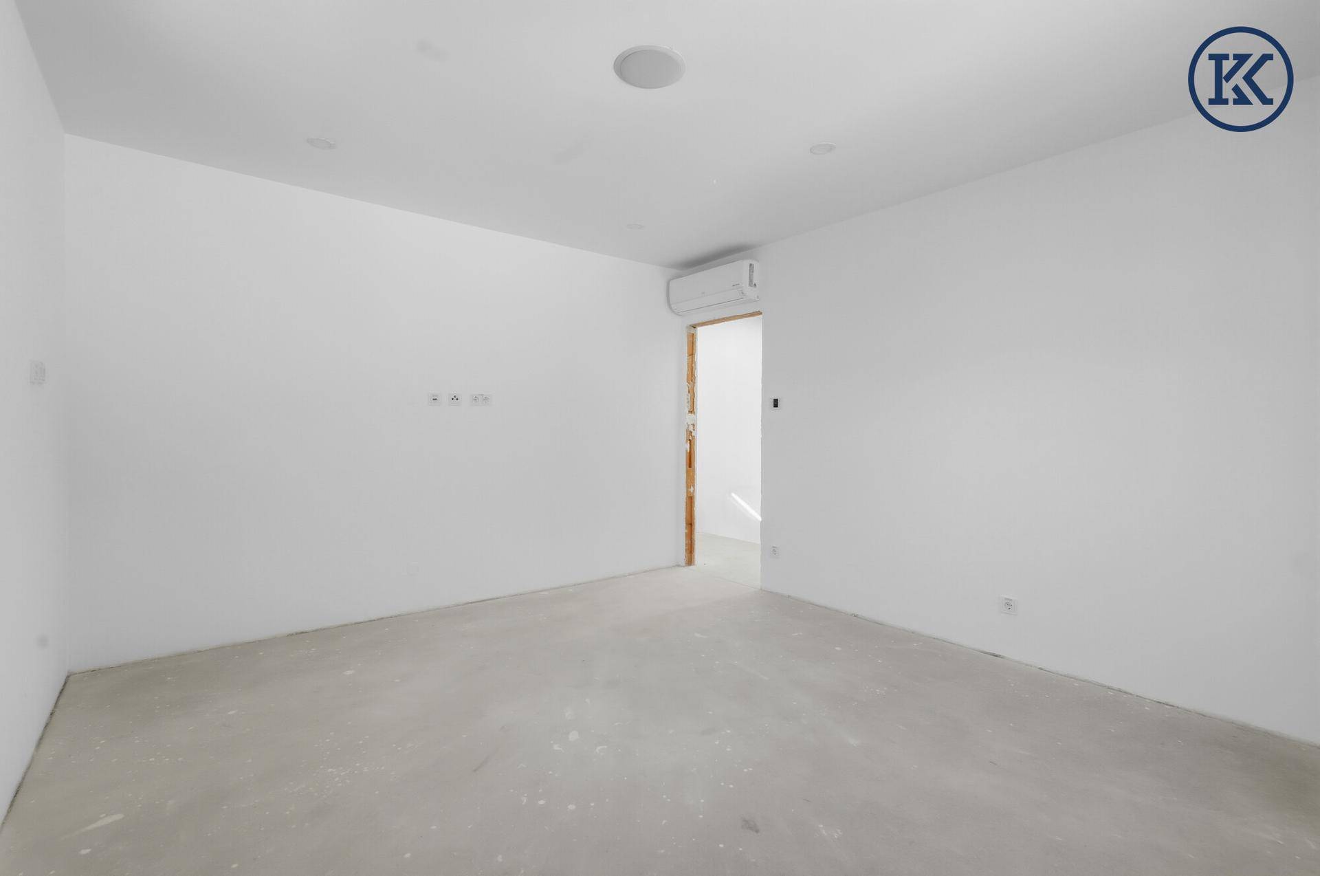 Leerer Raum im Neubau mit Klimaanlage und weiß gestrichenen Wänden, bereit für den Innenausbau.