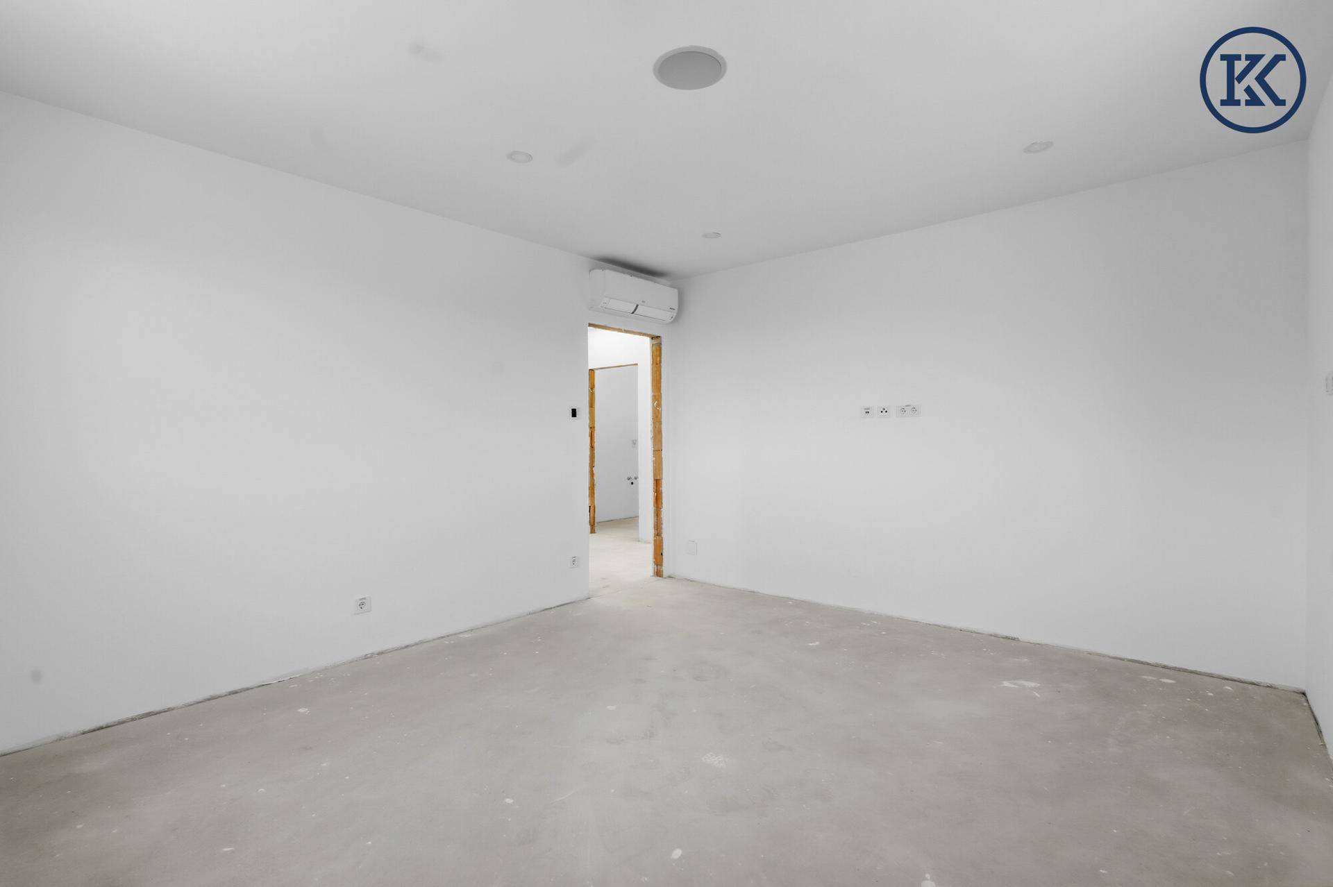 Leerer Raum im Neubau mit Klimaanlage und weiß gestrichenen Wänden, bereit für den Erstbezug.