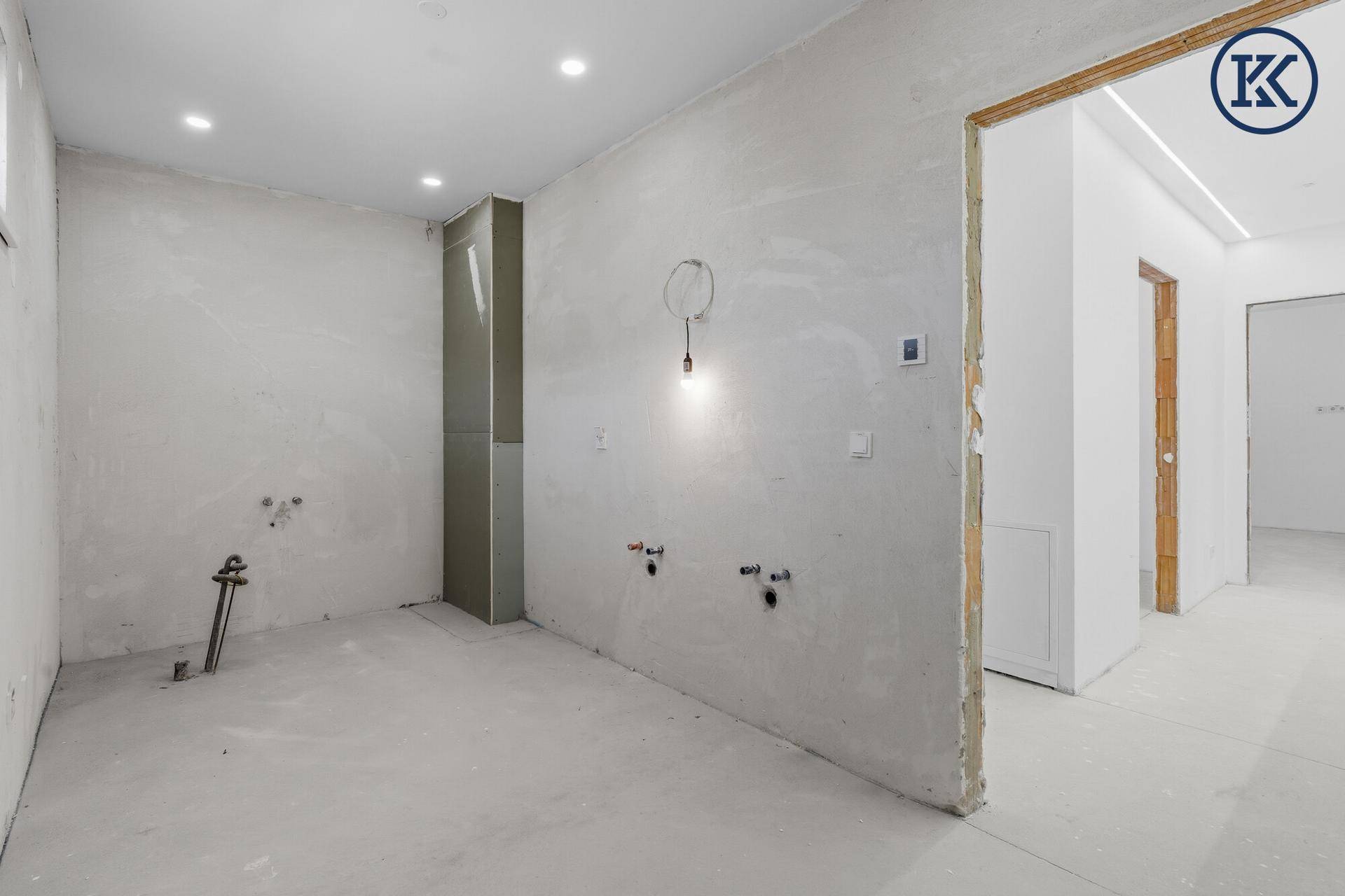Badezimmer im Rohbau mit vorbereiteten Anschlüssen für Waschbecken und Dusche, sowie Deckenstrahlern.