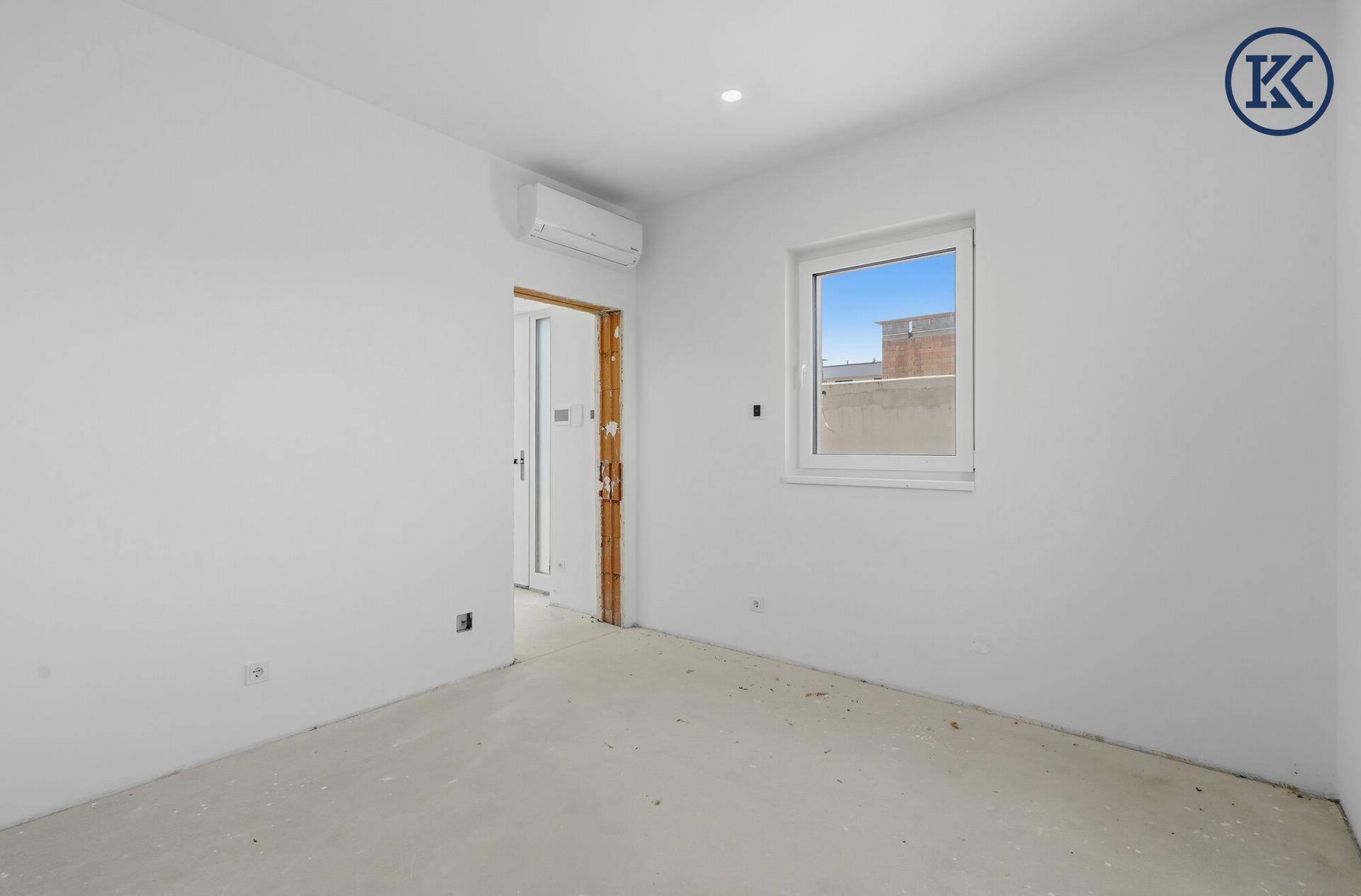 Helles Schlafzimmer im Rohbau mit Fenster und Vorbereitung für Klimaanlage.