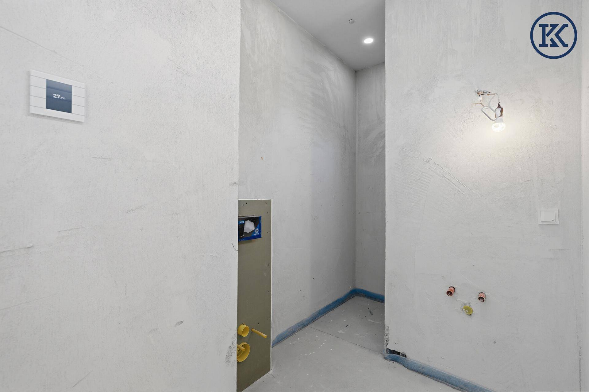 Kleiner Raum im Rohbau mit Vorinstallationen für ein WC und Wandthermostat.