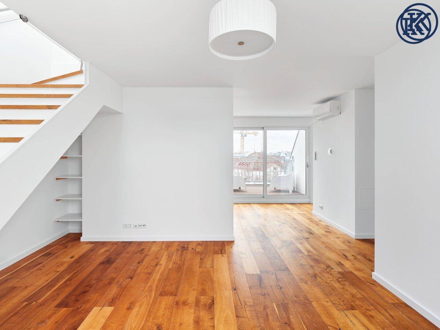 Heller Wohnbereich mit Holzboden, Treppe und Zugang zu einem Balkon mit Stadtblick.