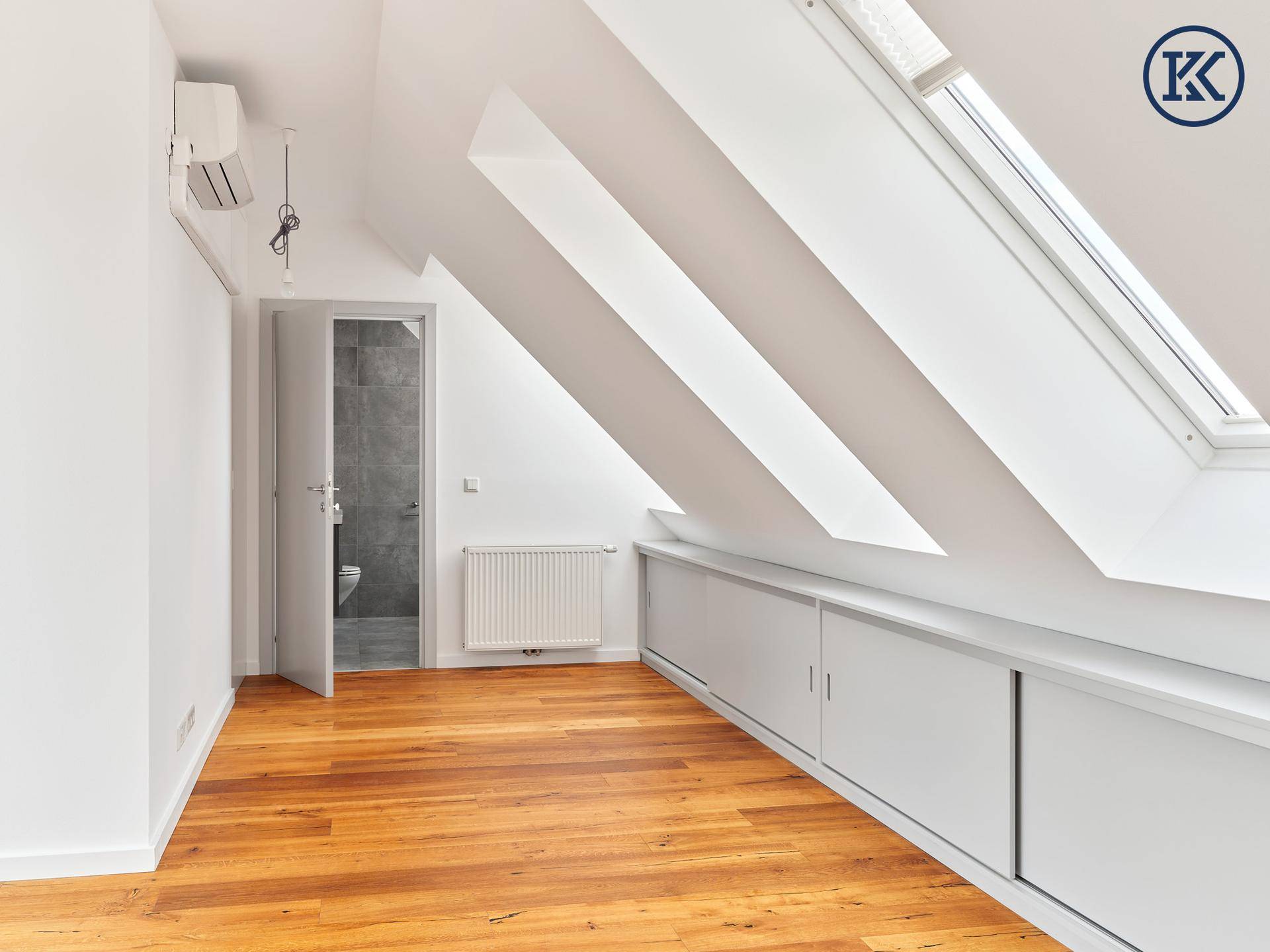 Lichtdurchflutetes Dachzimmer mit Holzboden, Dachfenstern und praktischen Einbauschränken.