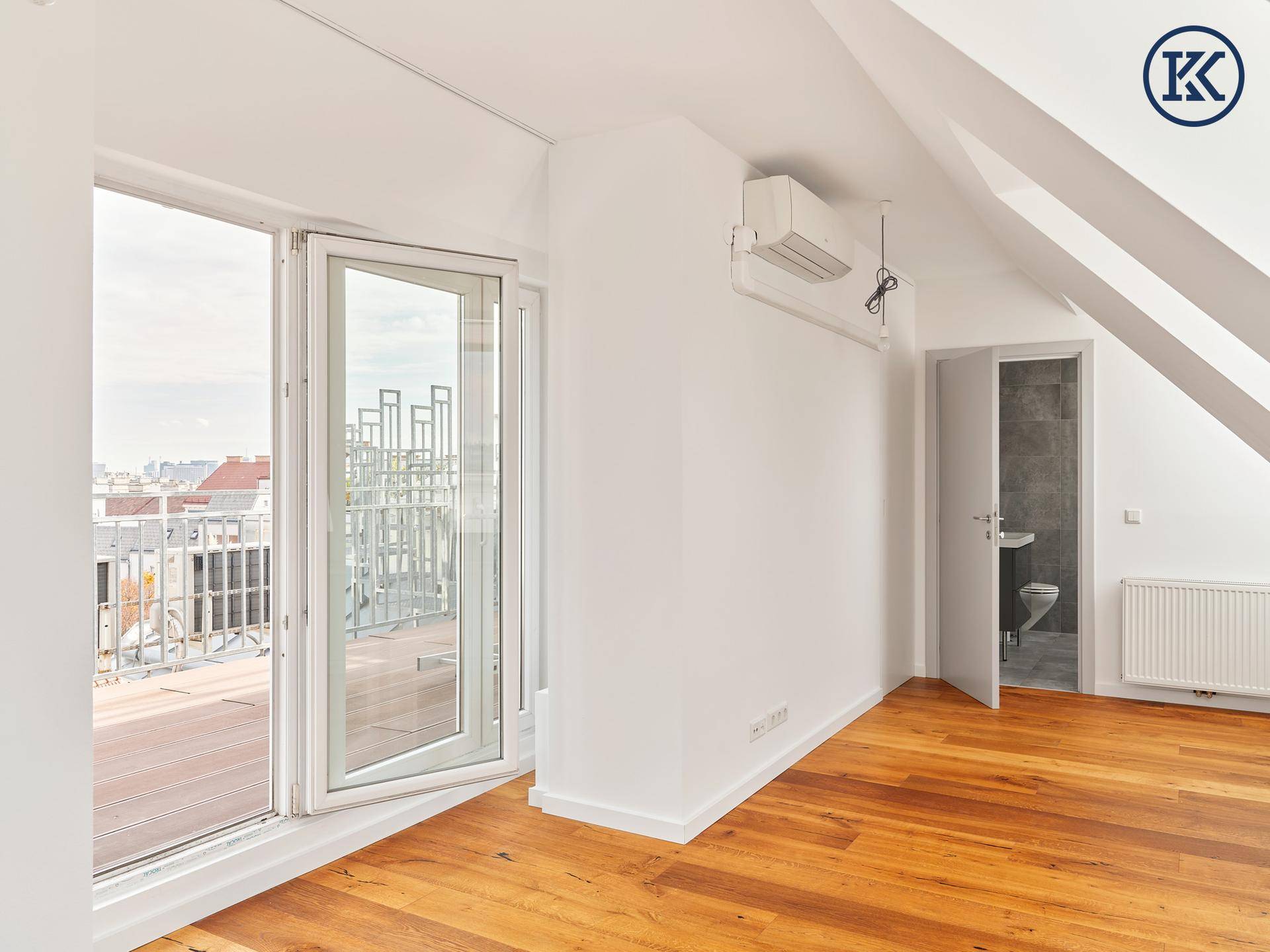 Helles Dachzimmer mit Holzboden, Dachschrägen und großen Fenstern zum Terrassenzugang.