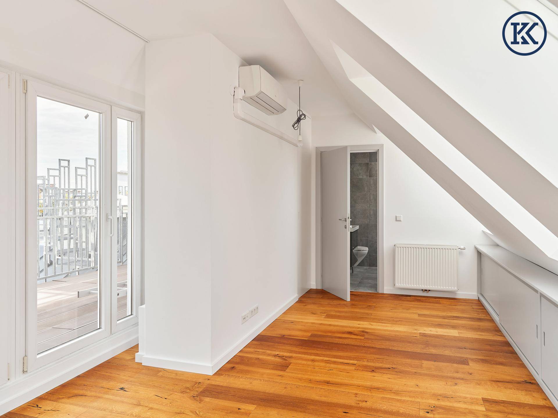 Geräumiges Dachzimmer mit Holzboden, Dachschrägen, Einbauschränken und Zugang zur Terrasse.