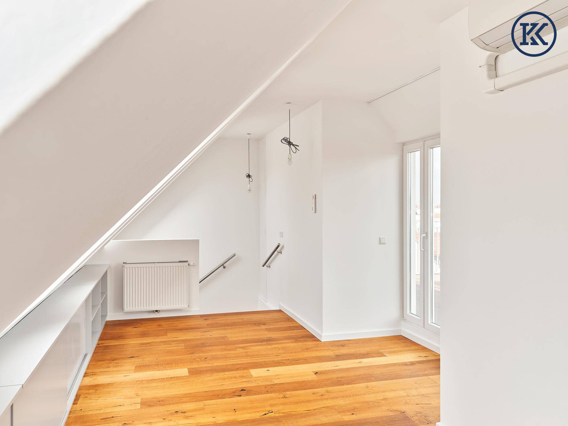 Helles Dachzimmer mit Holzboden, Dachschrägen und Heizkörper, bereit zur individuellen Gestaltung.