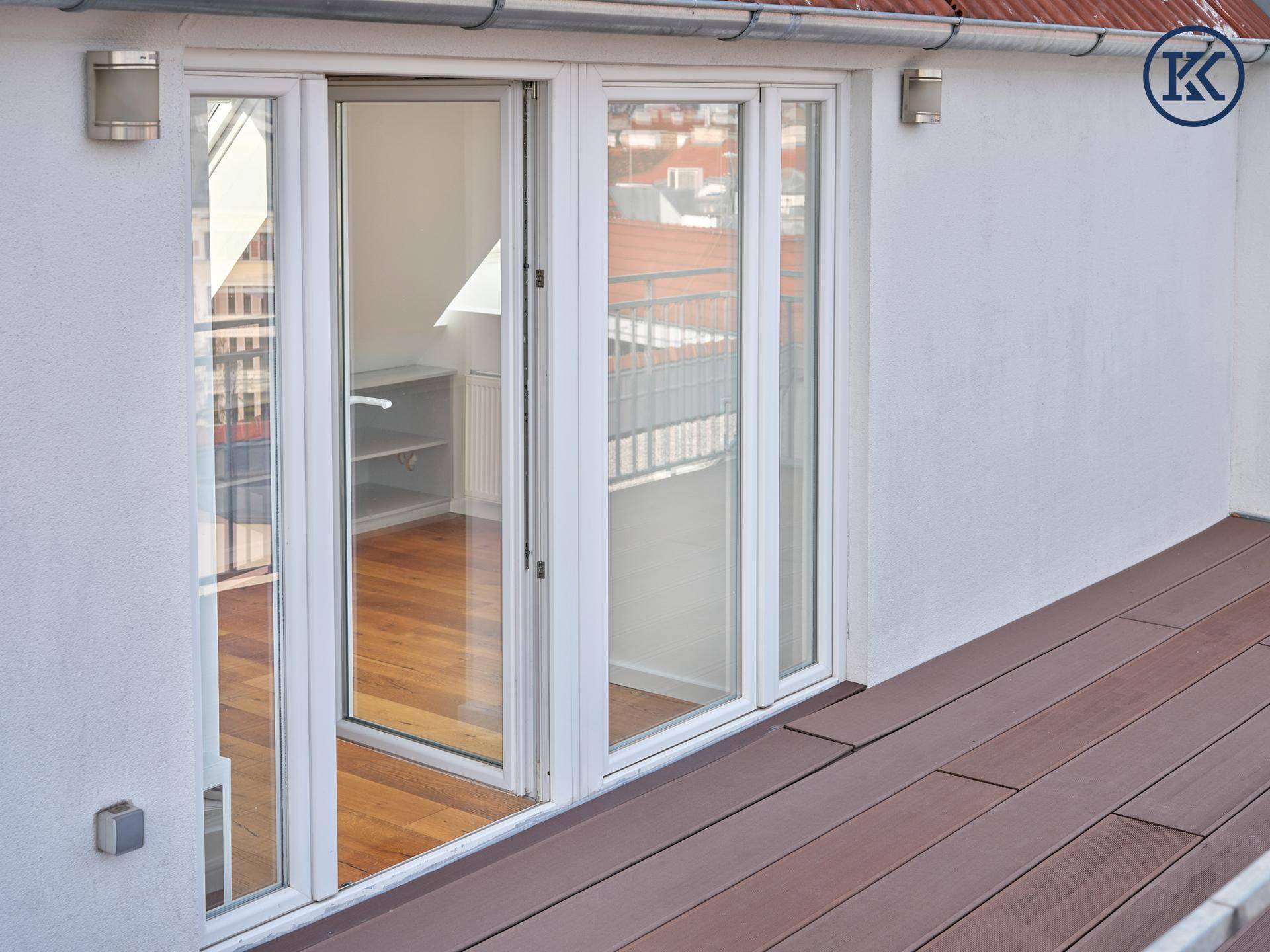 Helle Terrasse mit Holzboden und großem Schiebefenster zum Innenbereich mit Parkett.