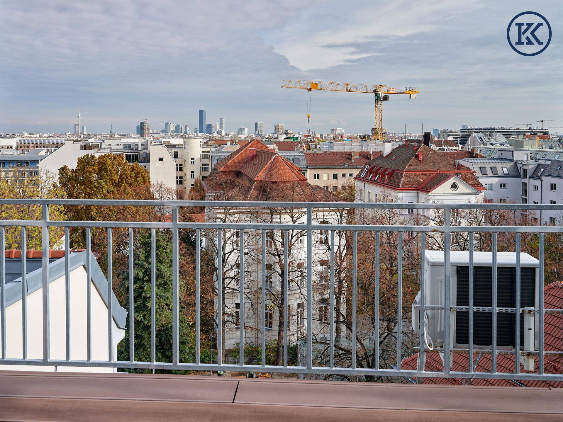 Weitläufiger Stadtblick von der Dachterrasse mit urbaner Skyline, Gebäuden und einem Kran.