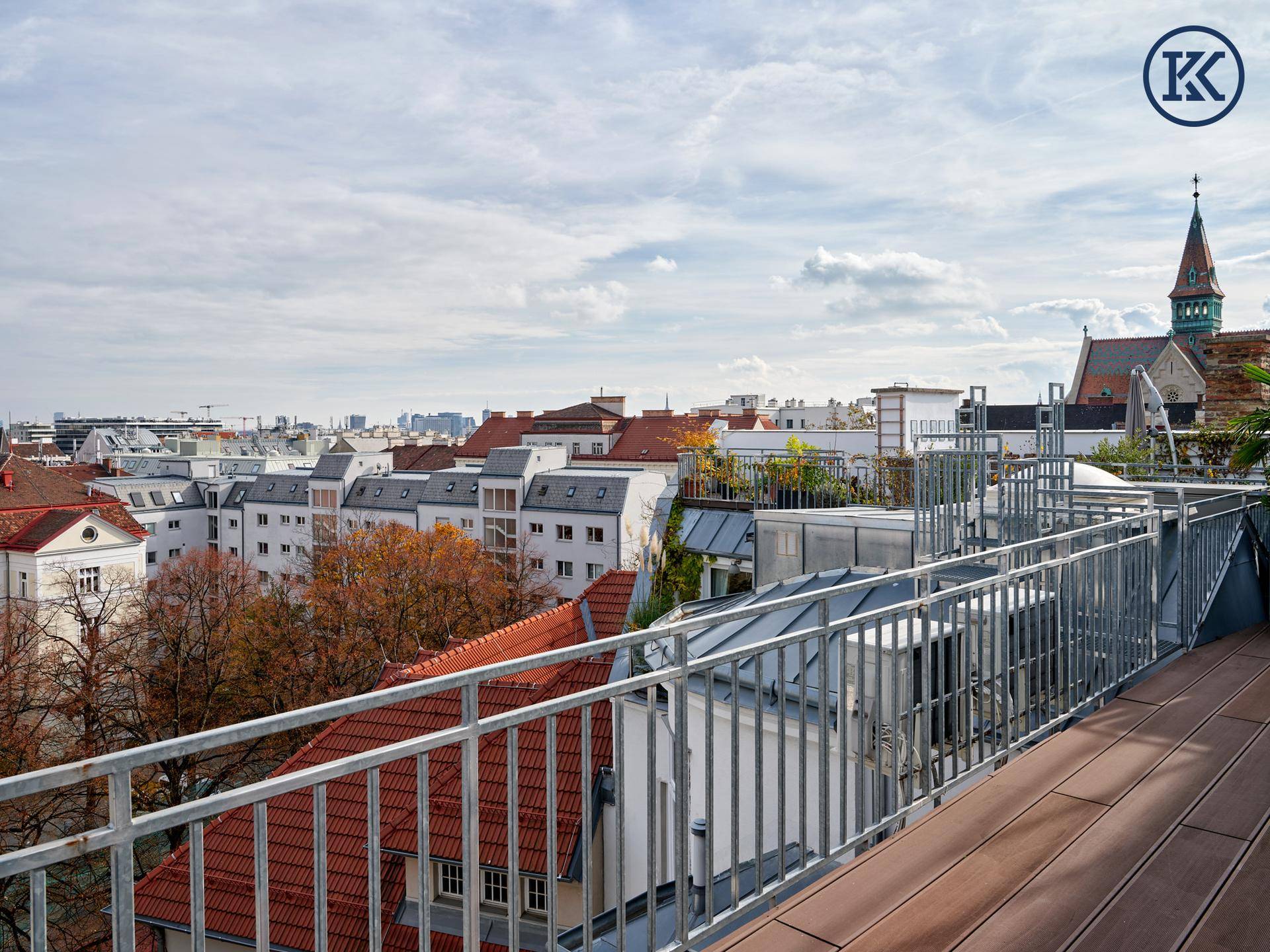 Helle Dachterrasse mit Holzboden und weitem Blick über die umliegenden Dächer der Stadt und Kirche.