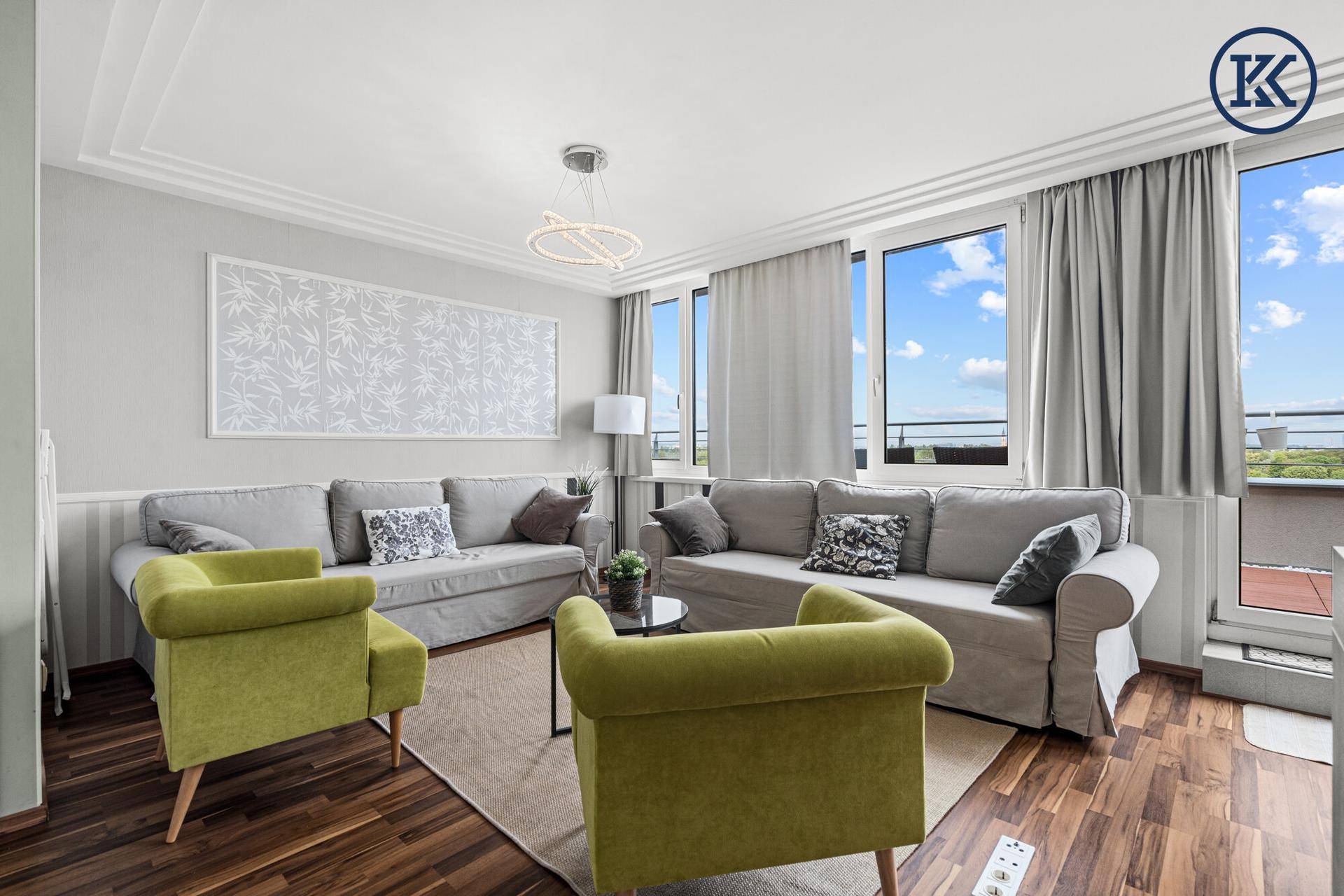 Helles Wohnzimmer mit großen Fenstern, bequemen Sofas und modernem Deckenlicht.