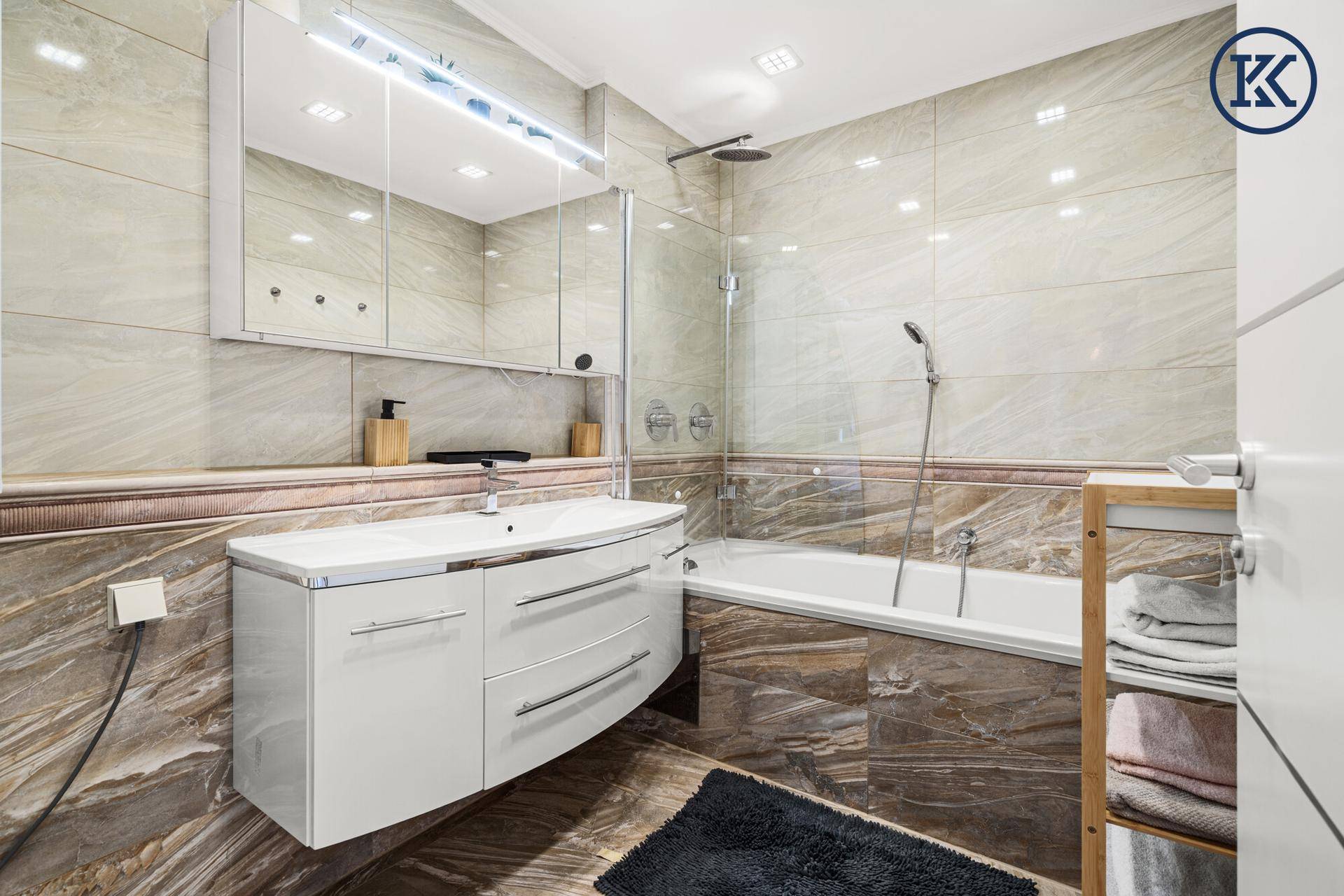 Modernes Badezimmer mit Badewanne, Duschfunktion und eleganten Fliesen.