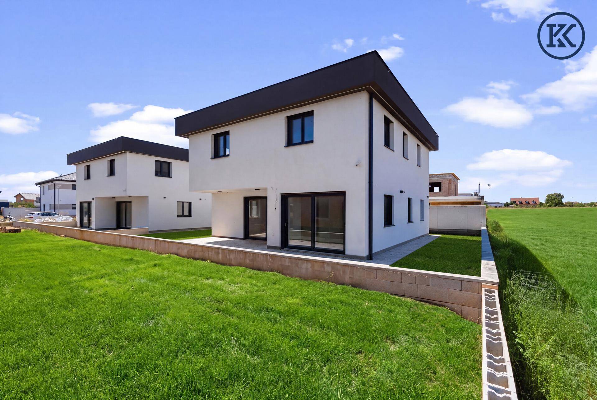 Neubau-Doppelhaushälfte mit weißer Fassade und frischem Rasen im Garten, bereit zur weiteren Gestaltung.