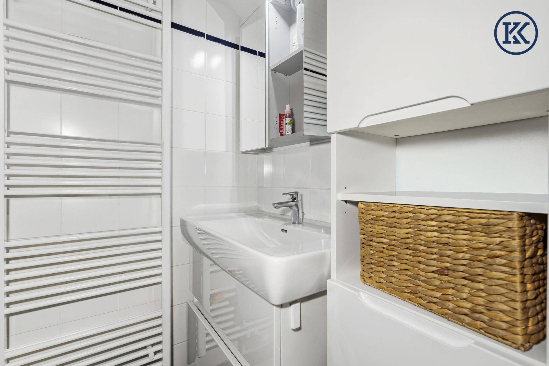 Helles Badezimmer mit modernem Waschbecken, Spiegelschrank und weißen Fliesen.