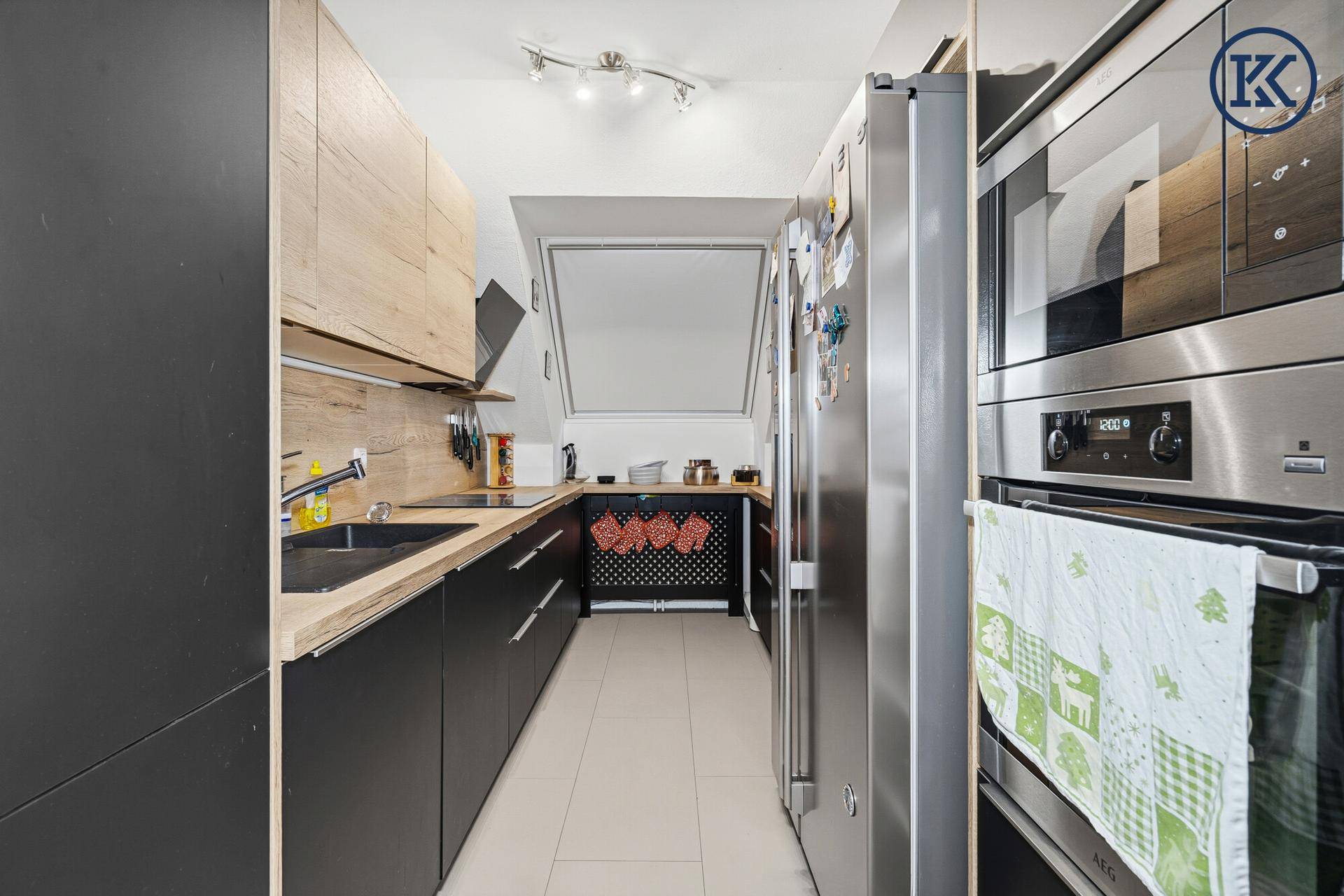 Moderne Küche im Dachgeschoss mit schwarzen und holzfarbenen Schränken und Dachfenster.