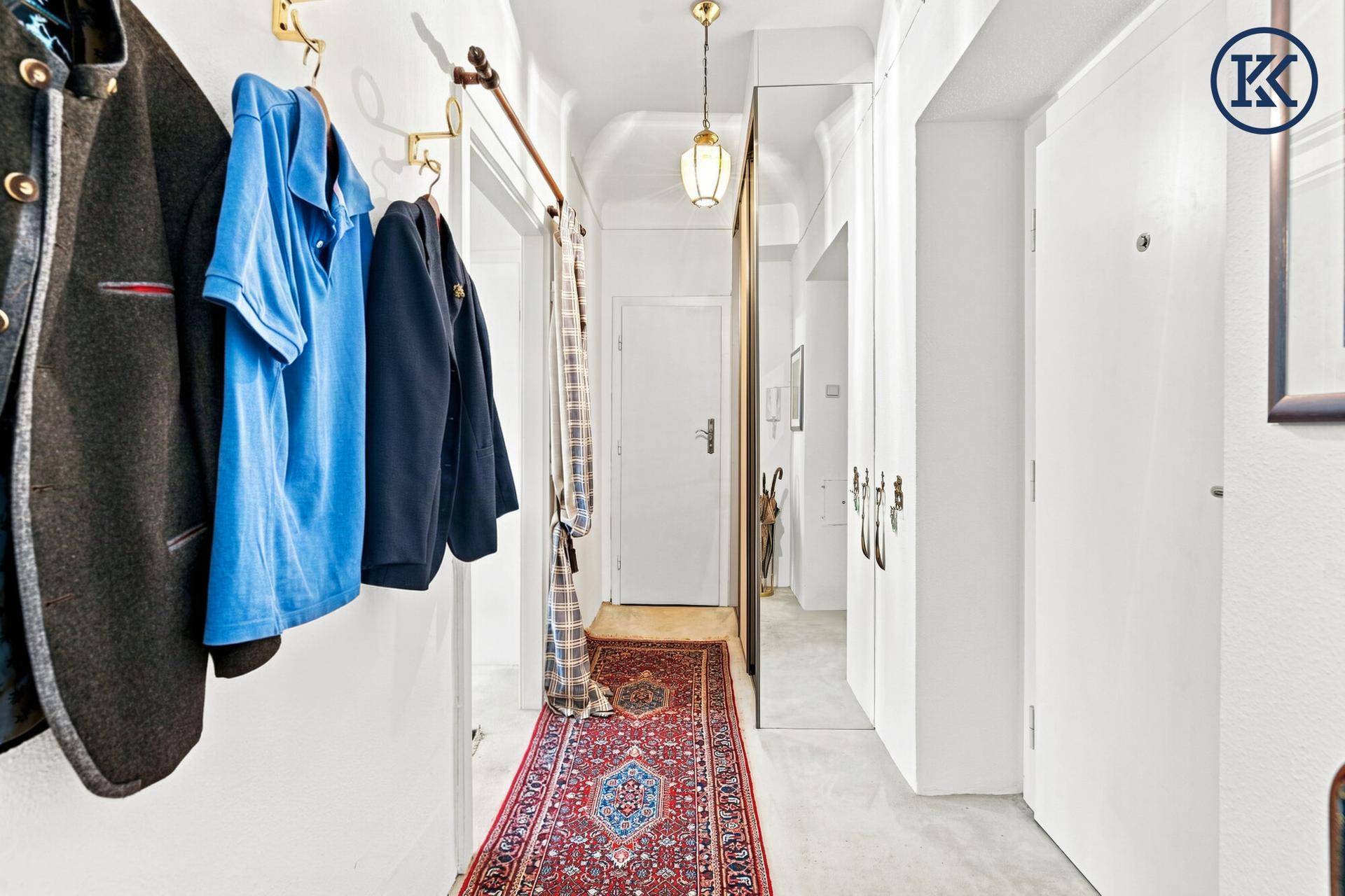 Heller Flur mit Garderobe, großem Spiegel und traditionellem Teppichläufer.