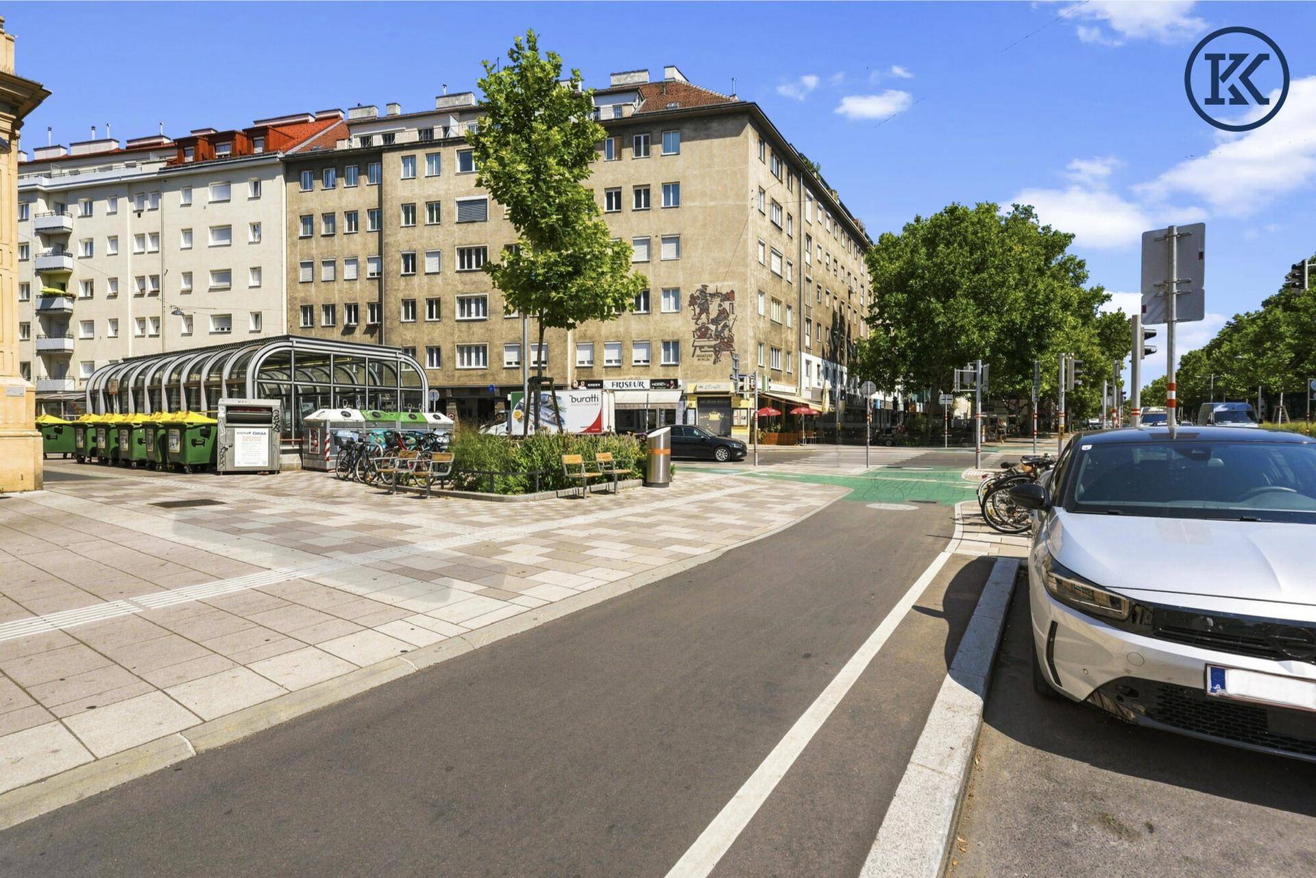 Weitläufige Straßenansicht mit U-Bahn-Station, Fahrradstellplätzen und historischen Gebäuden.