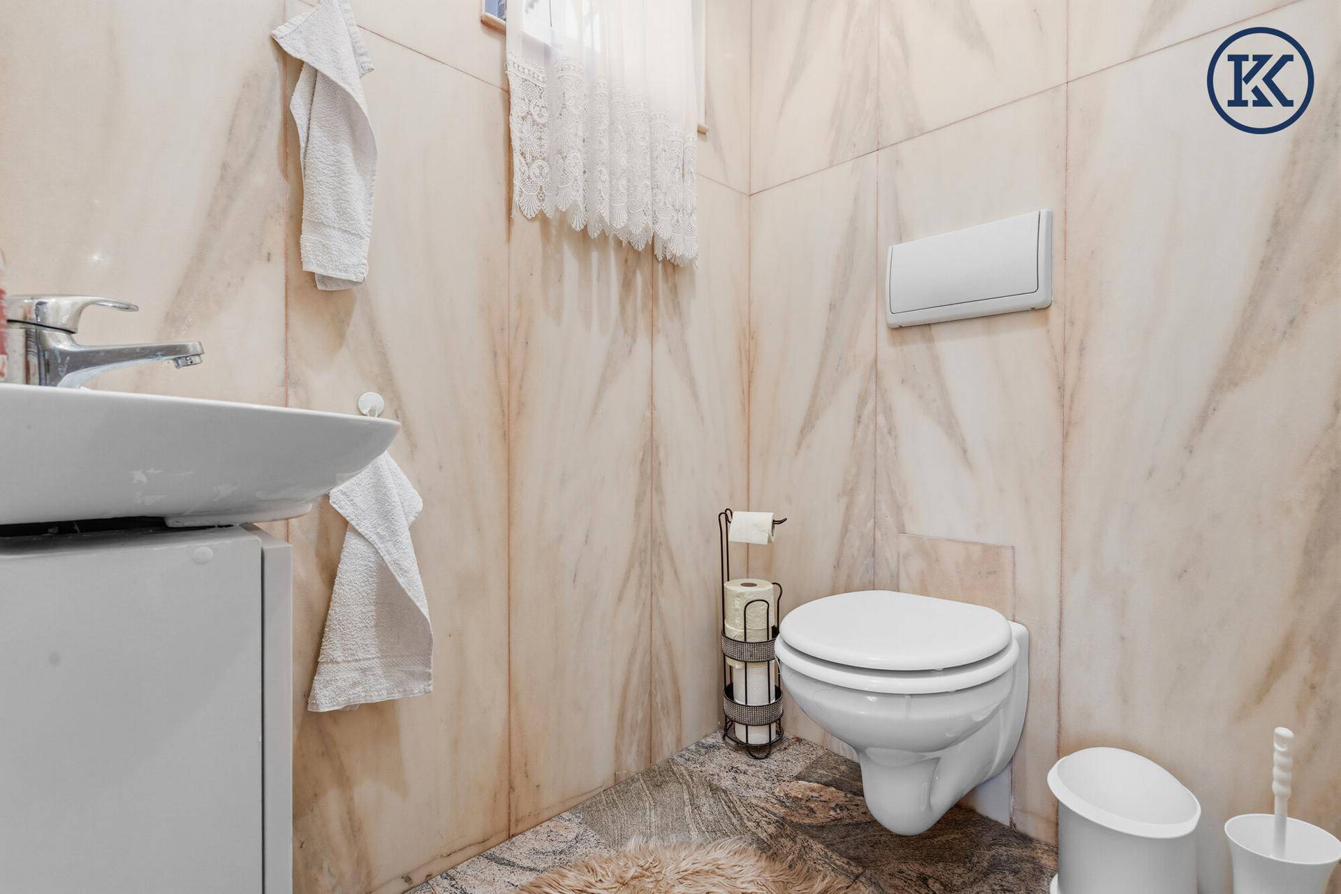 Kleines Gäste-WC mit Wand-WC, Waschbecken und gemusterten Fliesen.