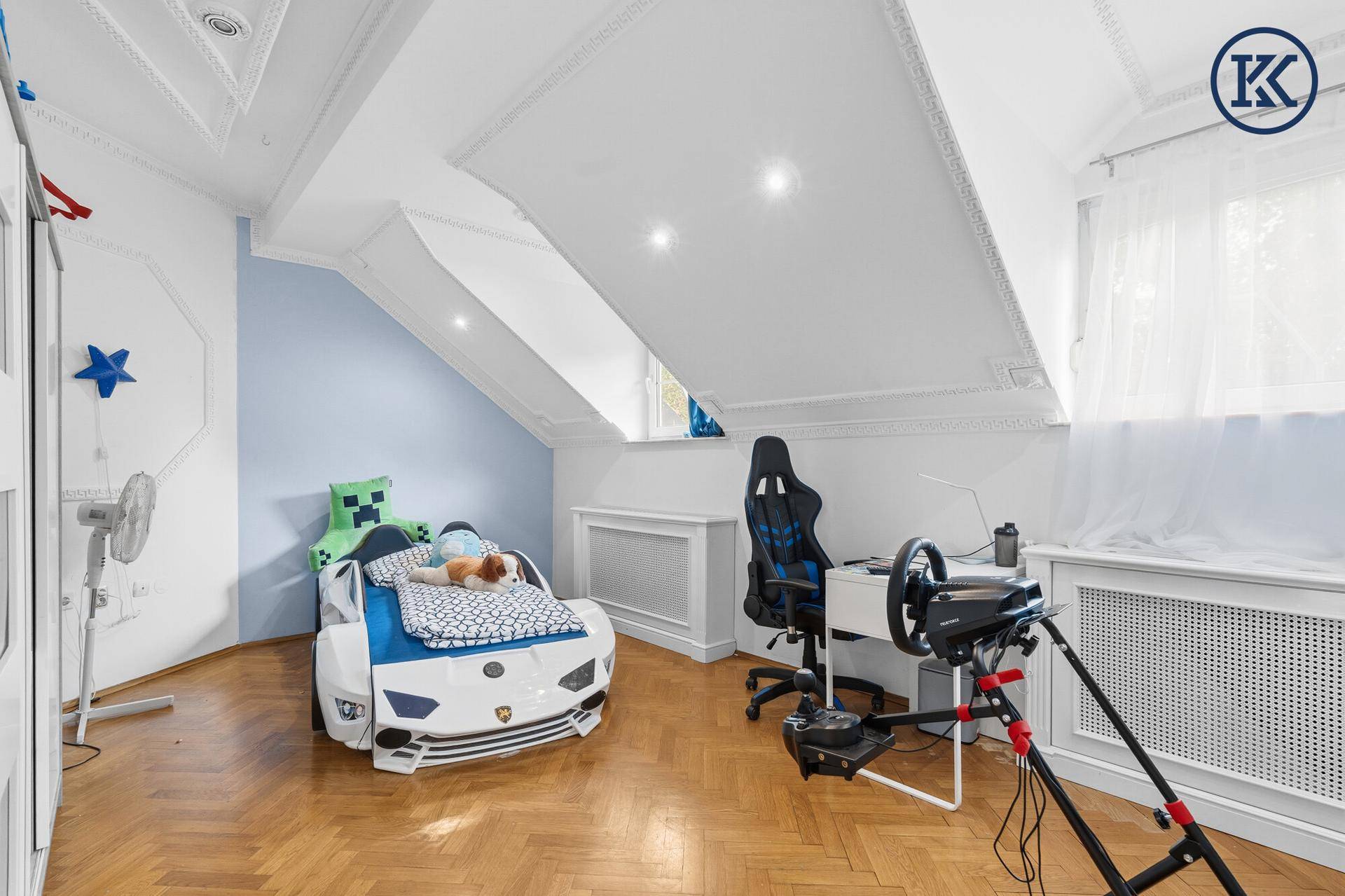 Kinderzimmer im Dachgeschoss mit Rennwagenbett, Schreibtisch und Dachschrägen.