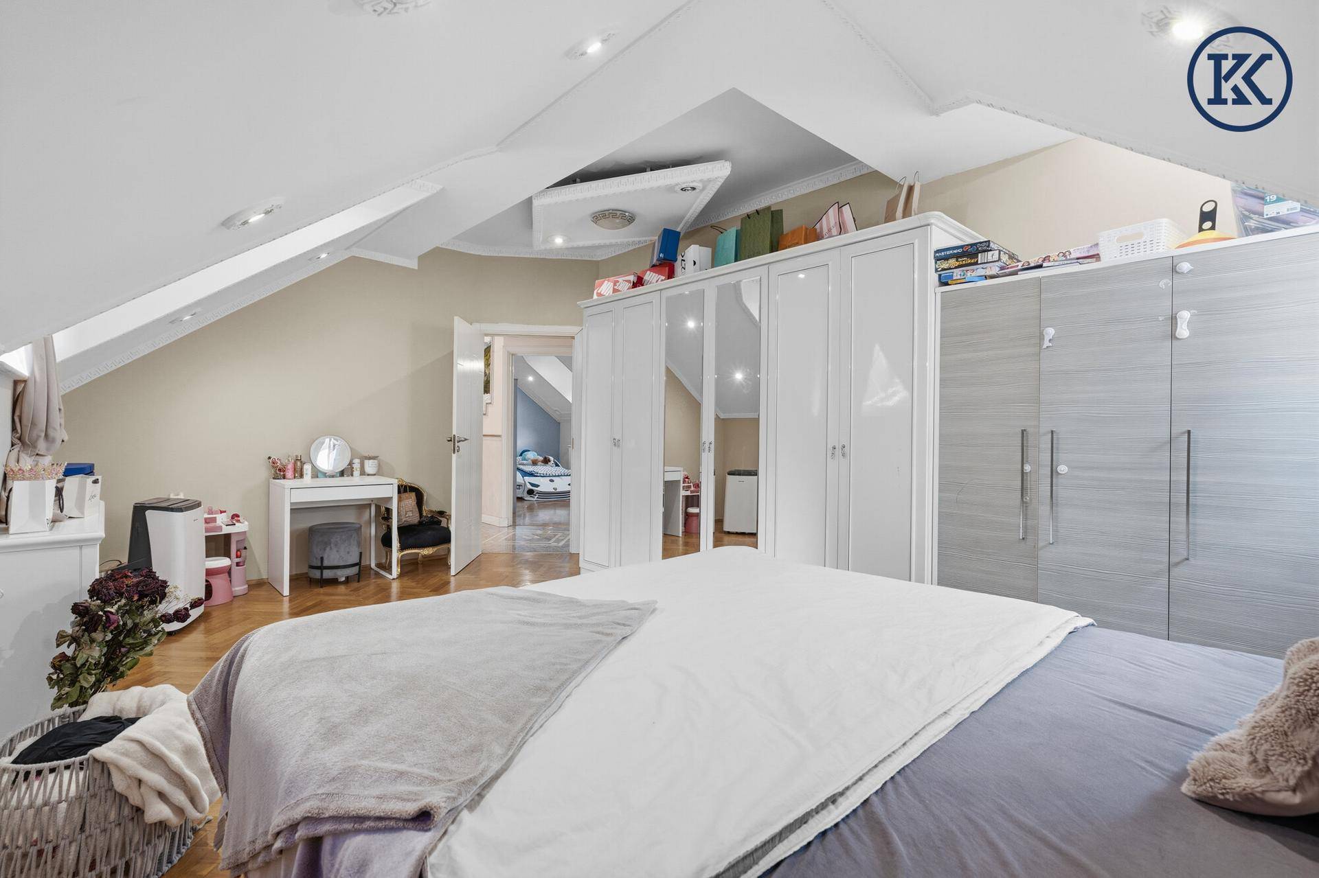 Schlafzimmer im Dachgeschoss mit Holzboden, Kleiderschränken und Zugang zu weiteren Räumen.