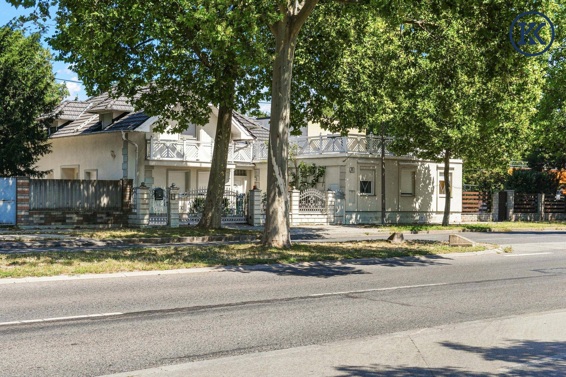 Einfamilienhaus mit gepflegter Fassade und Vorgarten, umgeben von Bäumen an einer Straße.