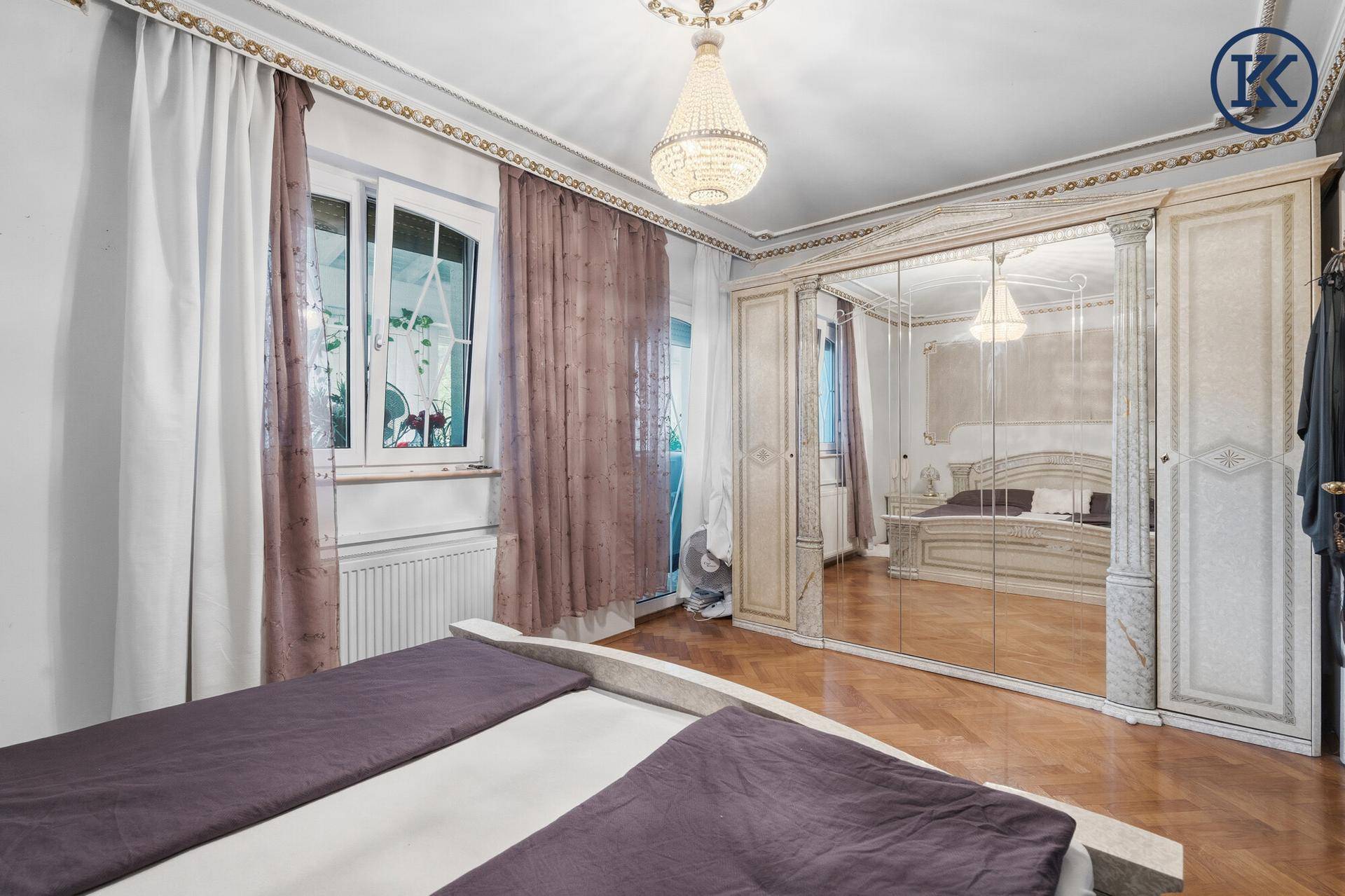 Schlafzimmer mit großem Spiegelschrank, Parkettboden und klassischer Einrichtung.