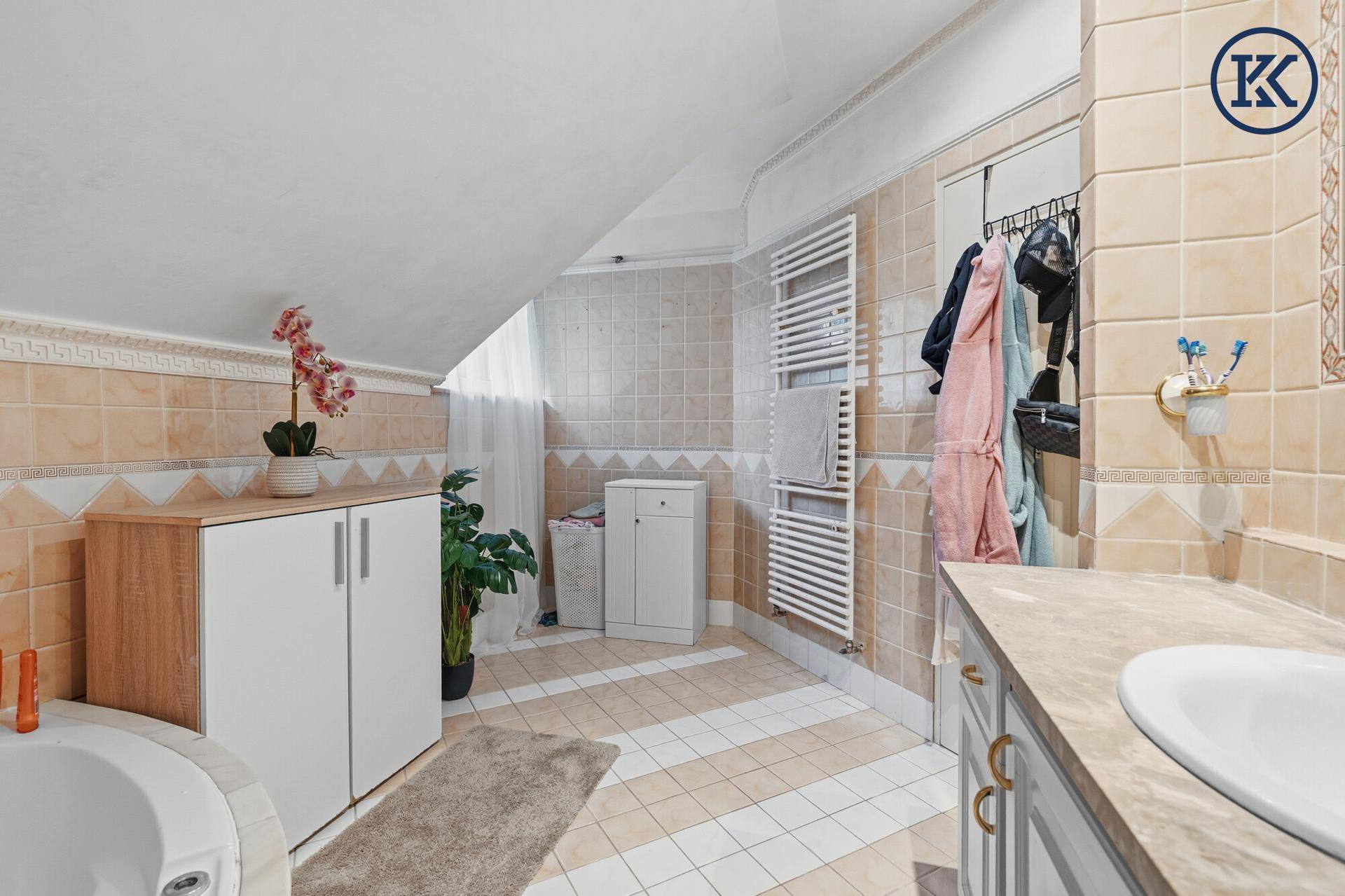 Badezimmer im Dachgeschoss mit beheiztem Handtuchhalter, Waschtisch und beigefarbenen Fliesen.